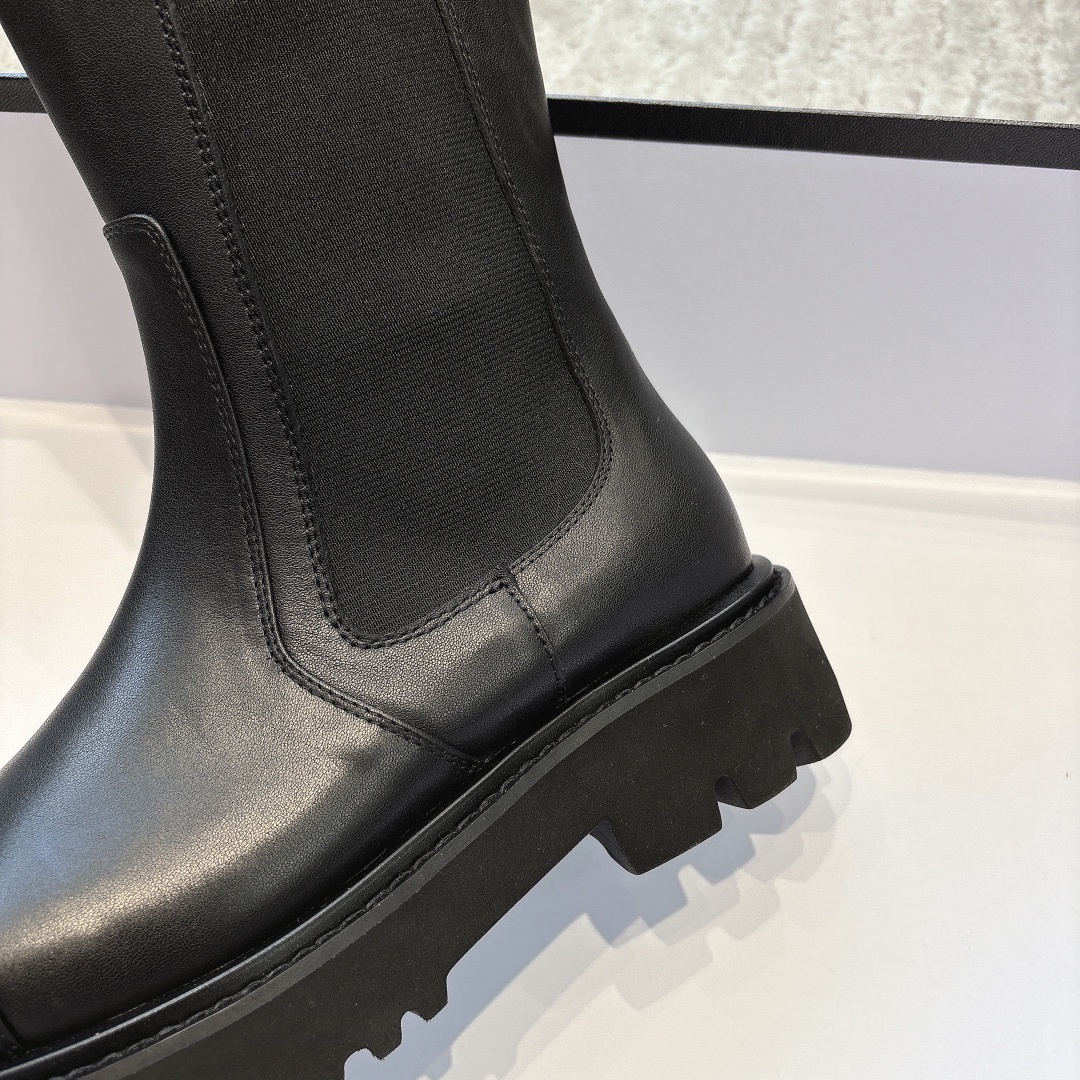 Chanel black leather knee-high boots with chunky lug soles and gold CC logo on a black box - Hình 9
