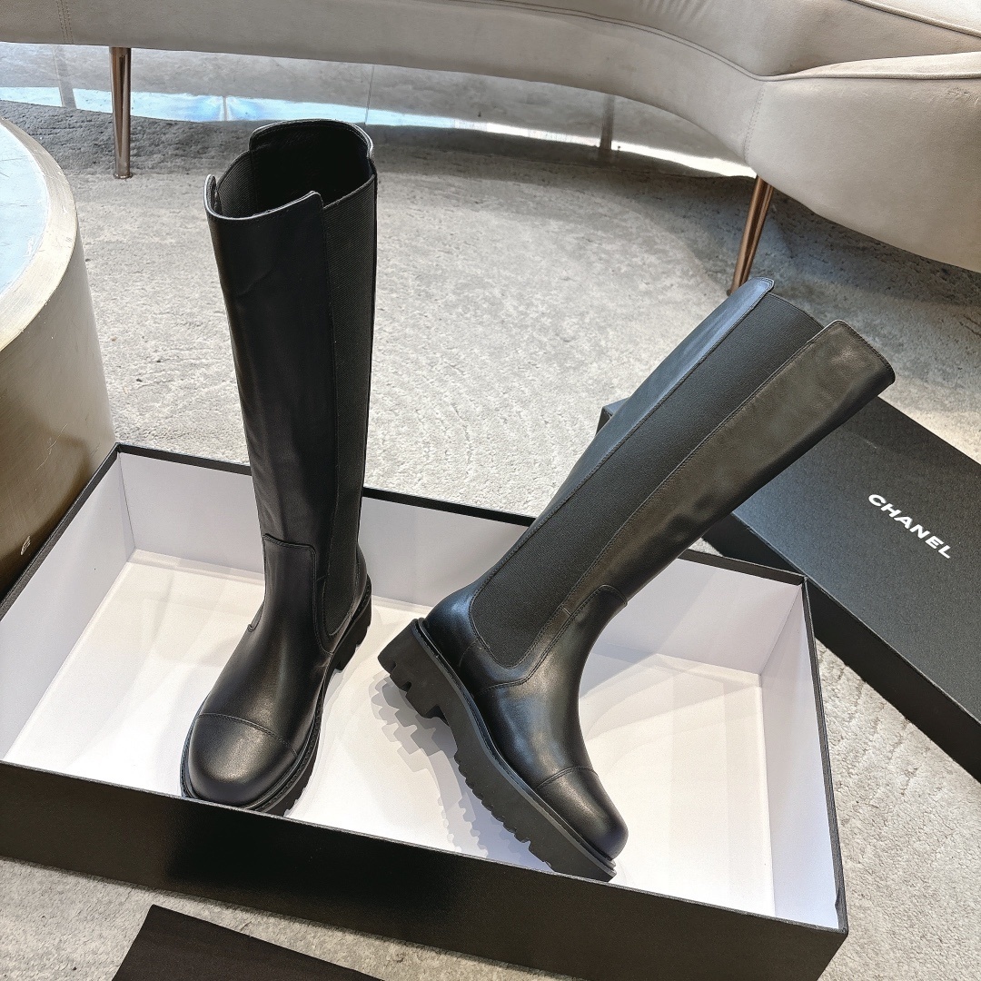 Chanel black leather knee-high boots with chunky lug soles and gold CC logo on a black box - Hình 3