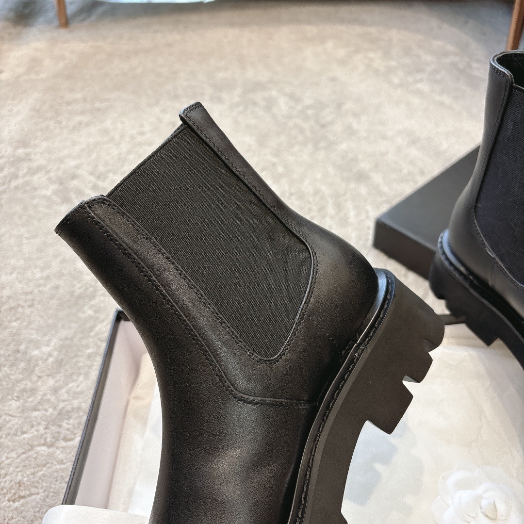 A pair of high-end black leather Chelsea boots with thick lug soles shown in a designer box with white ribbons. - Hình 8