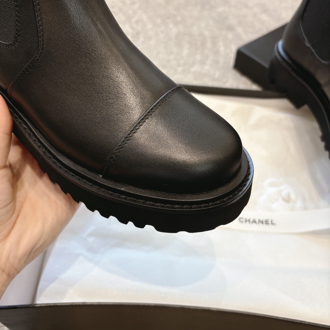 A pair of high-end black leather Chelsea boots with thick lug soles shown in a designer box with white ribbons. - Hình 7