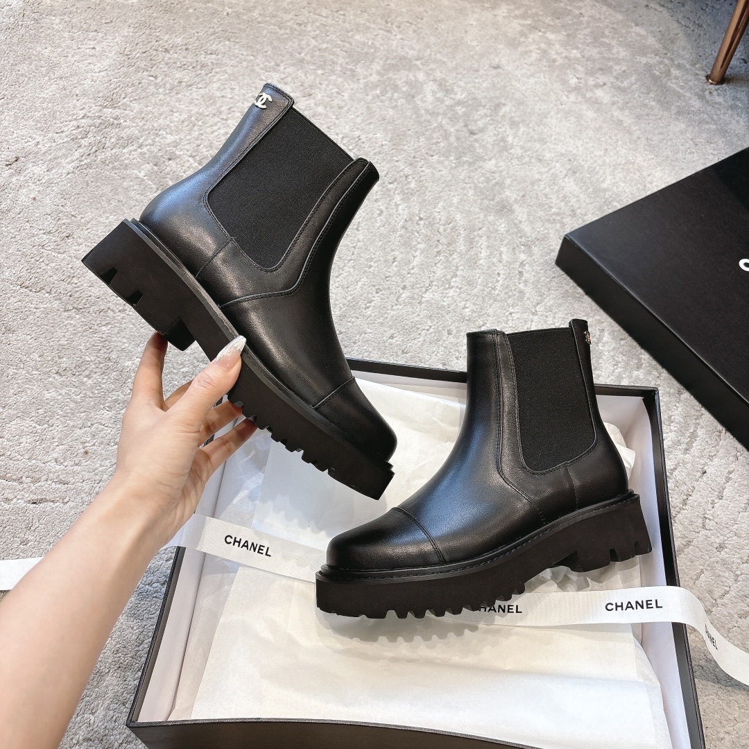 A pair of high-end black leather Chelsea boots with thick lug soles shown in a designer box with white ribbons. - Hình 6