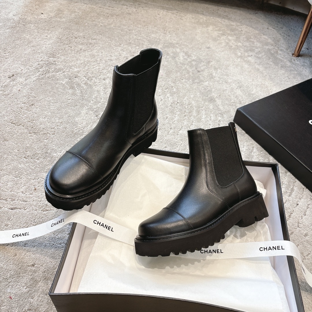 A pair of high-end black leather Chelsea boots with thick lug soles shown in a designer box with white ribbons. - Hình 3