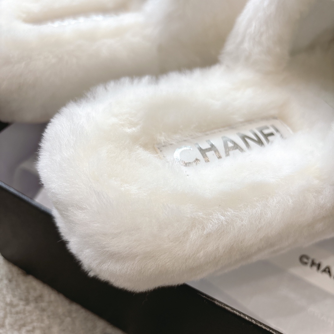 A pair of plush white faux fur slippers with a designer logo embroidery in a black gift box with white ribbon. - Hình 8