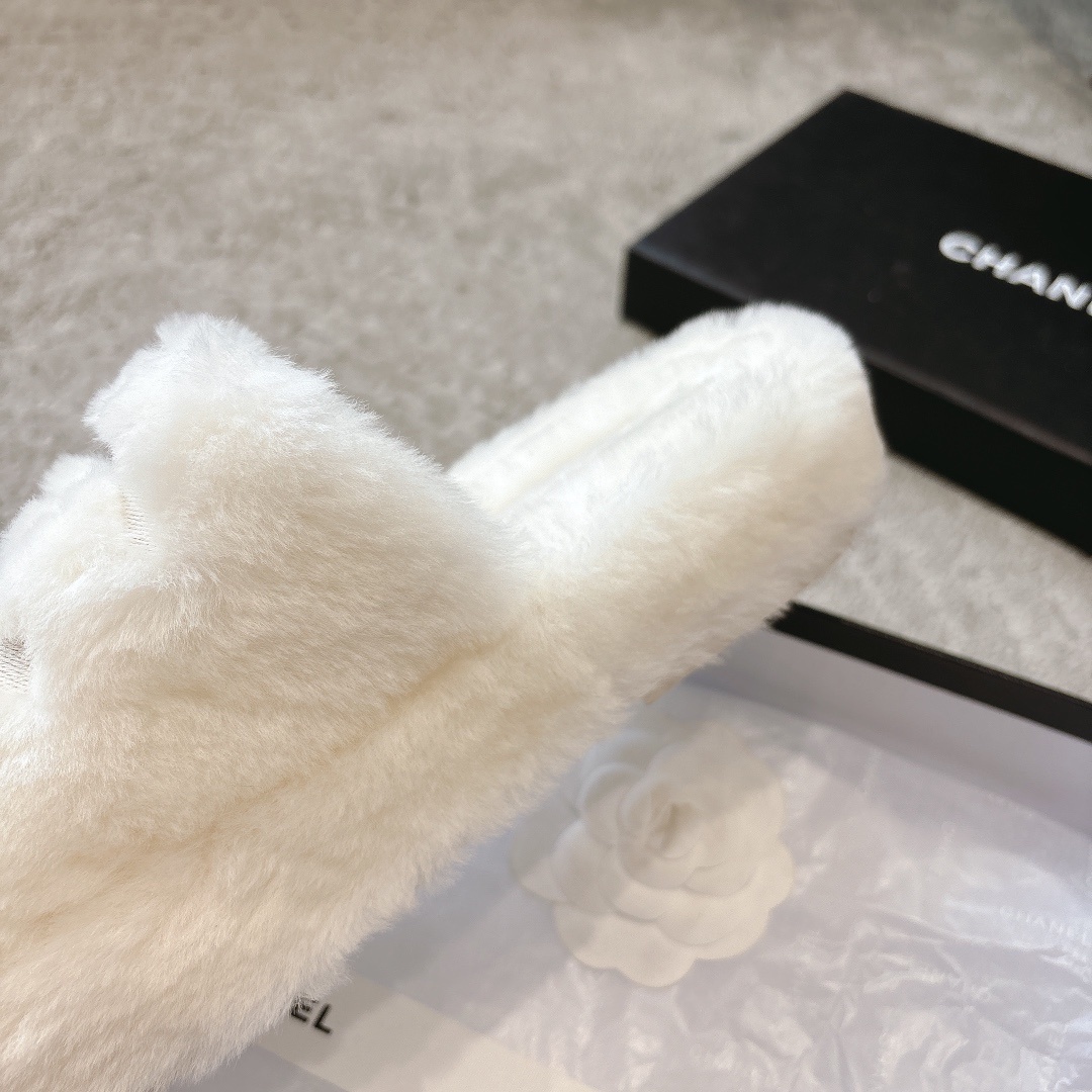 A pair of plush white faux fur slippers with a designer logo embroidery in a black gift box with white ribbon. - Hình 7
