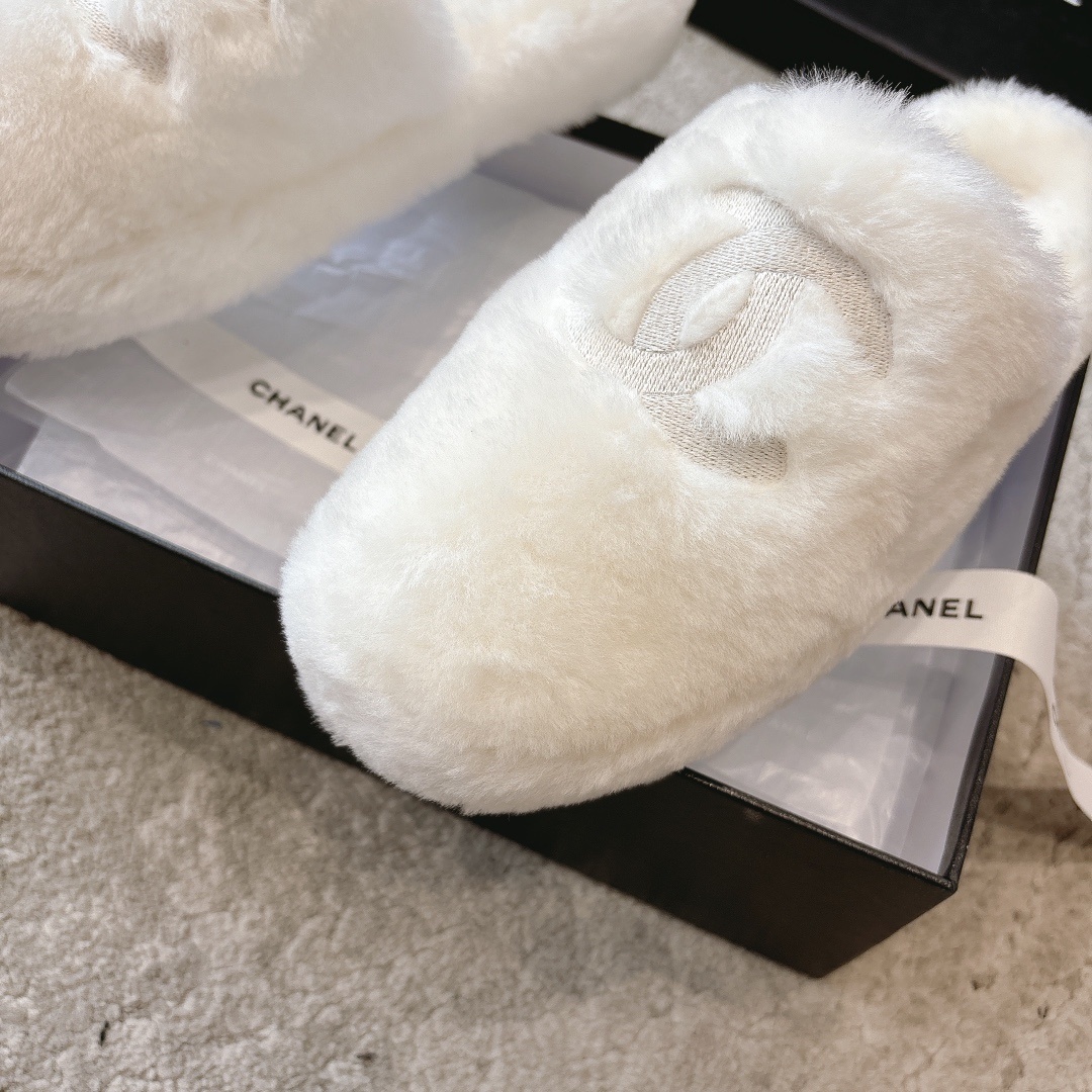 A pair of plush white faux fur slippers with a designer logo embroidery in a black gift box with white ribbon. - Hình 6