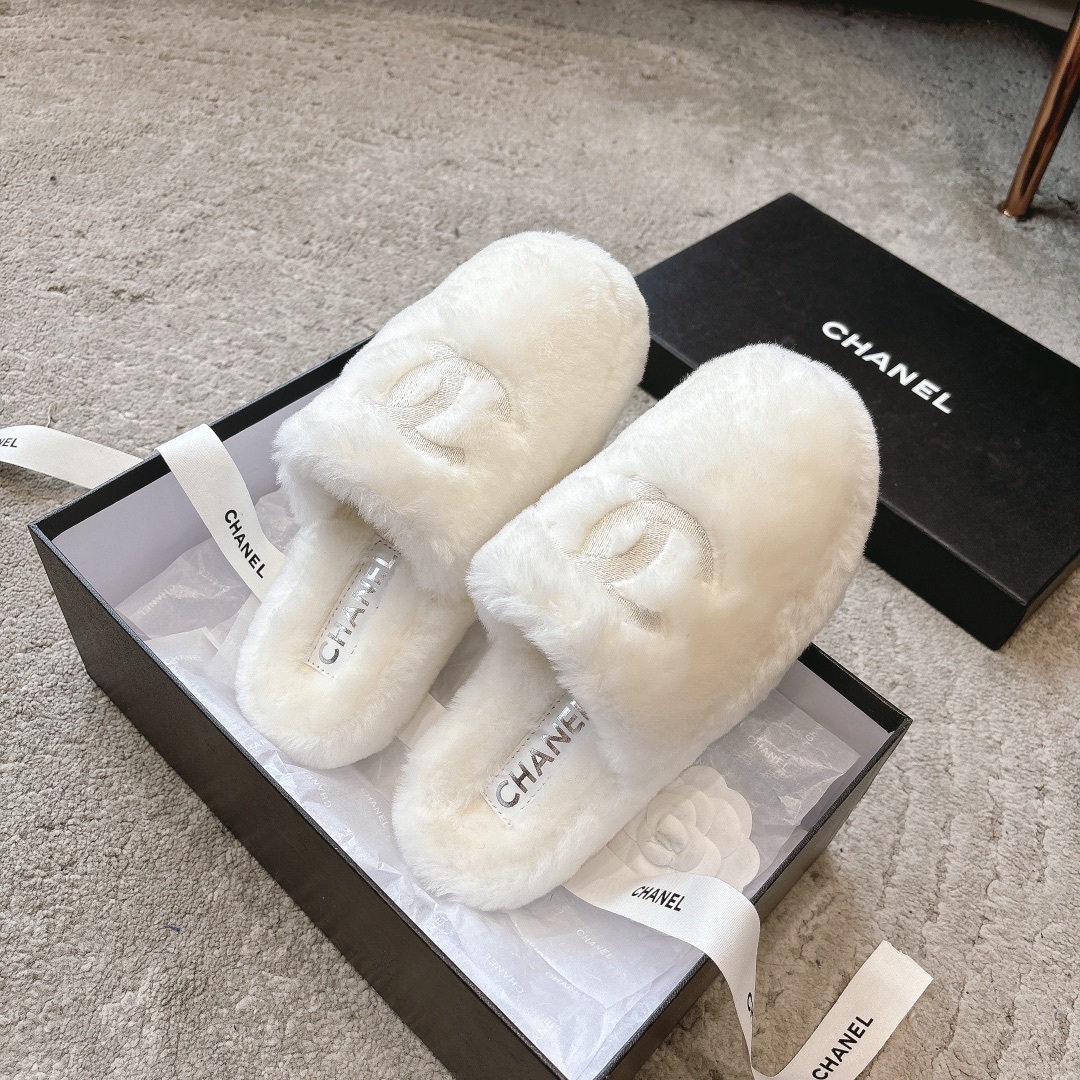A pair of plush white faux fur slippers with a designer logo embroidery in a black gift box with white ribbon. - Hình 5