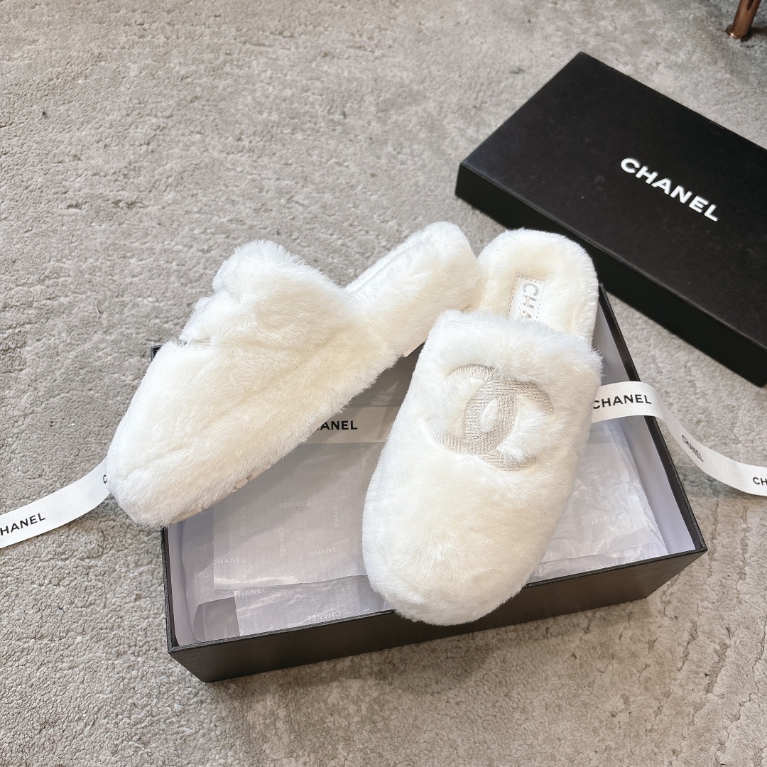 A pair of plush white faux fur slippers with a designer logo embroidery in a black gift box with white ribbon. - Hình 4