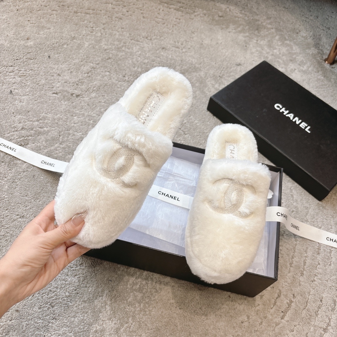 A pair of plush white faux fur slippers with a designer logo embroidery in a black gift box with white ribbon. - Hình 2
