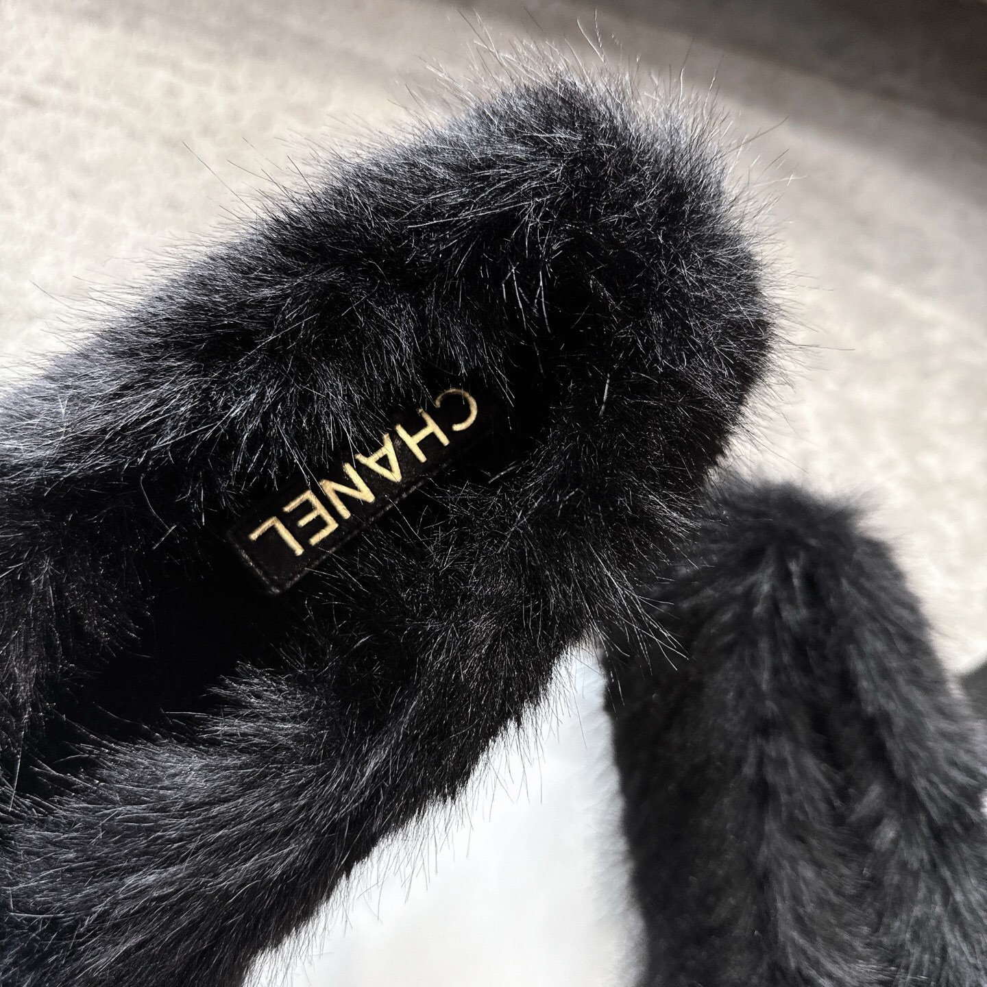 Top view of black Chanel fur loafers with white pom-poms on a grey carpet - Hình 8