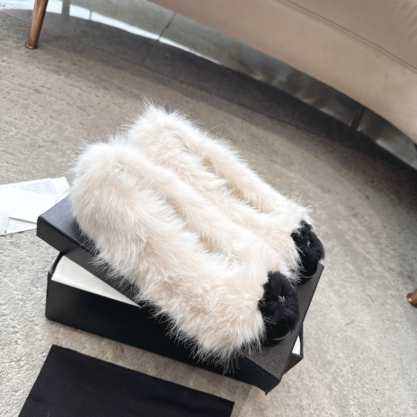 A pair of luxury white faux fur ballerina flats with black toe caps and silver CC logos, presented in a designer box. - Hình 6