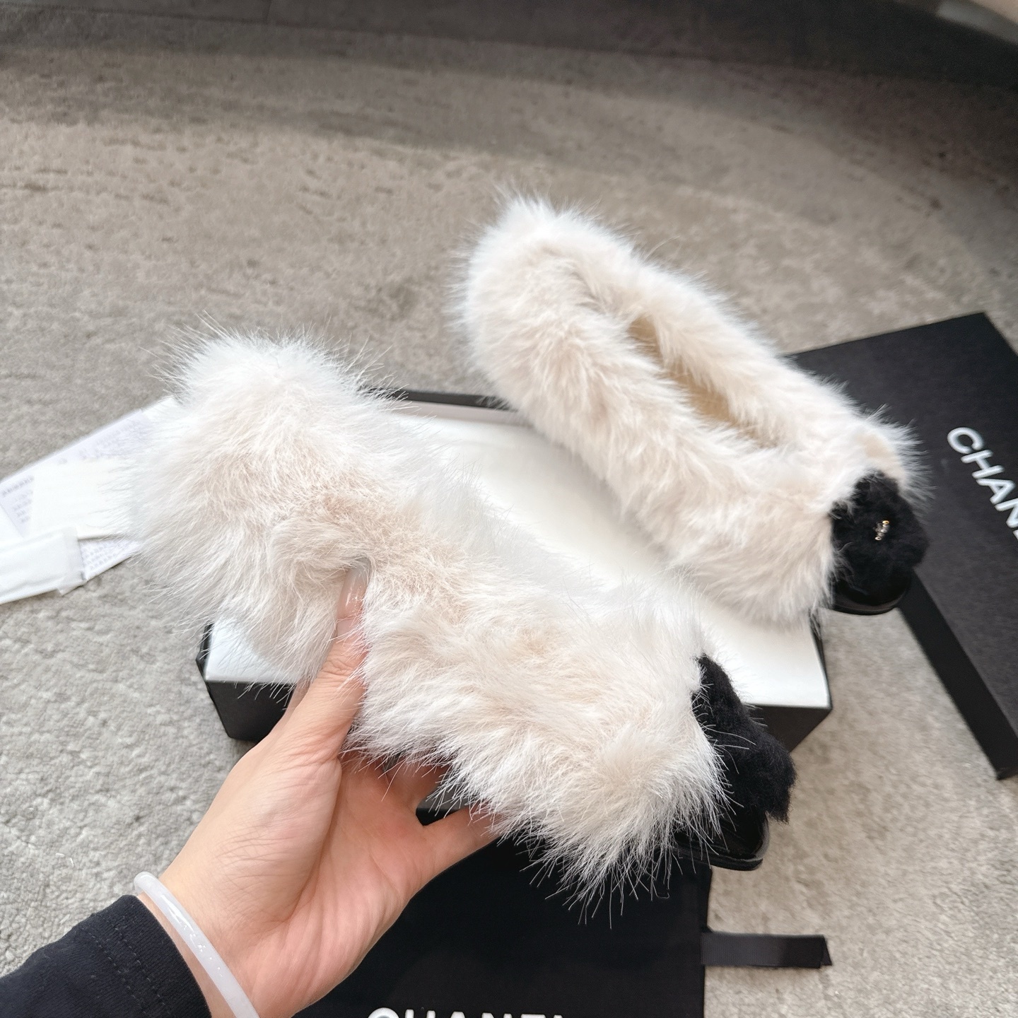 A pair of luxury white faux fur ballerina flats with black toe caps and silver CC logos, presented in a designer box. - Hình 3