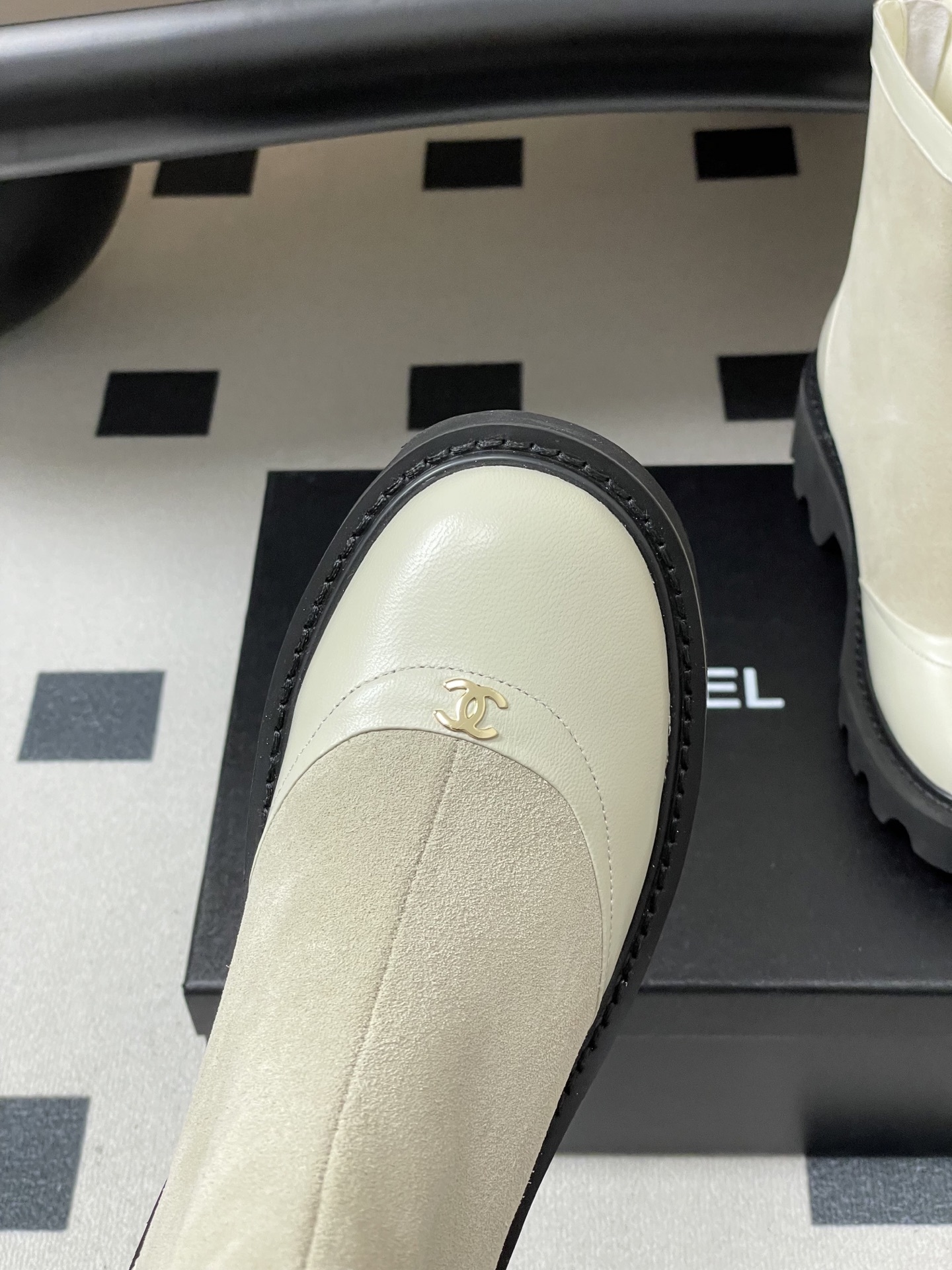 Pair of luxury off-white suede and leather ankle boots with black chunky lug soles and gold-tone logo detail on the toe cap. - Hình 6