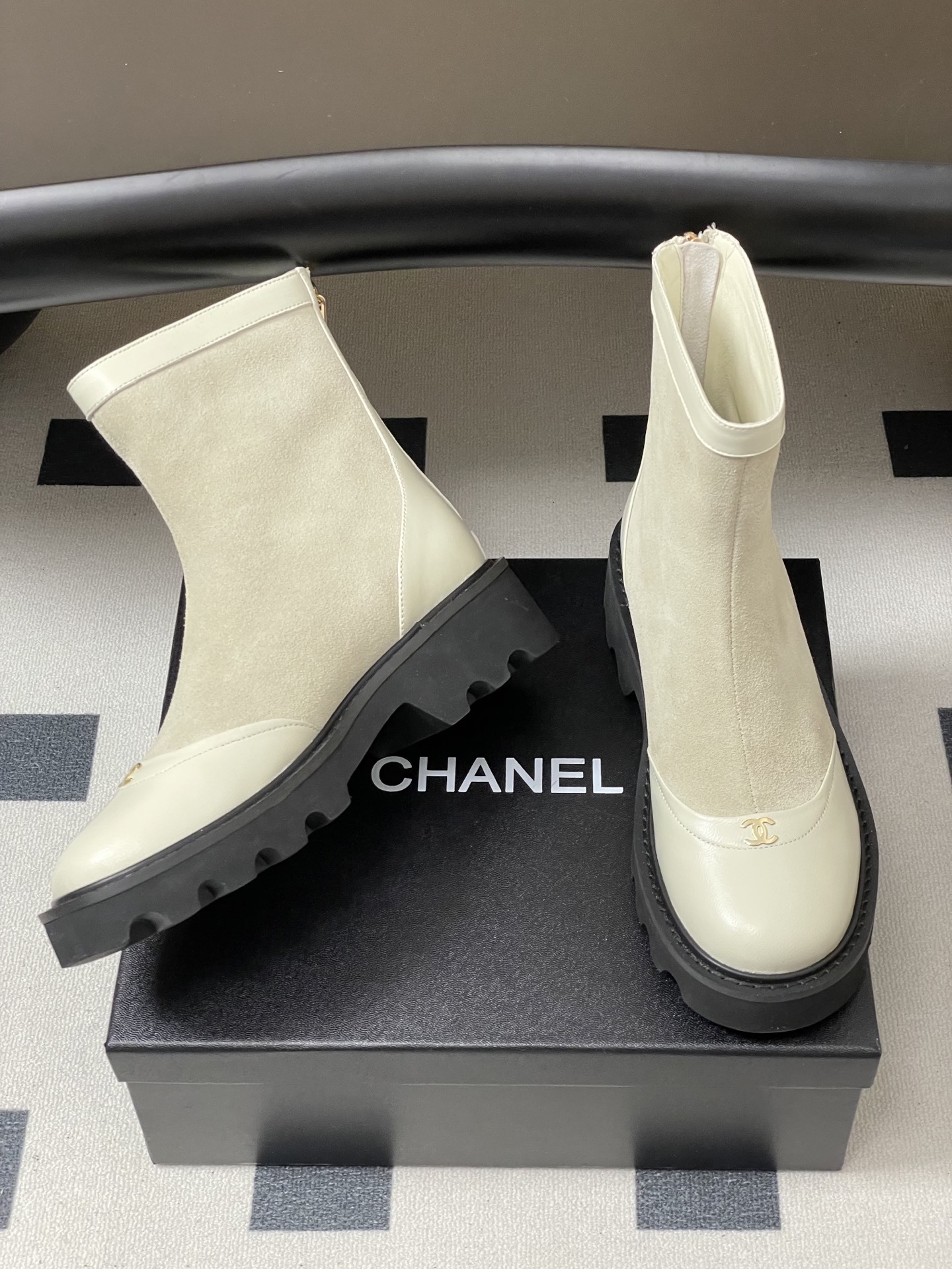 Pair of luxury off-white suede and leather ankle boots with black chunky lug soles and gold-tone logo detail on the toe cap. - Hình 5