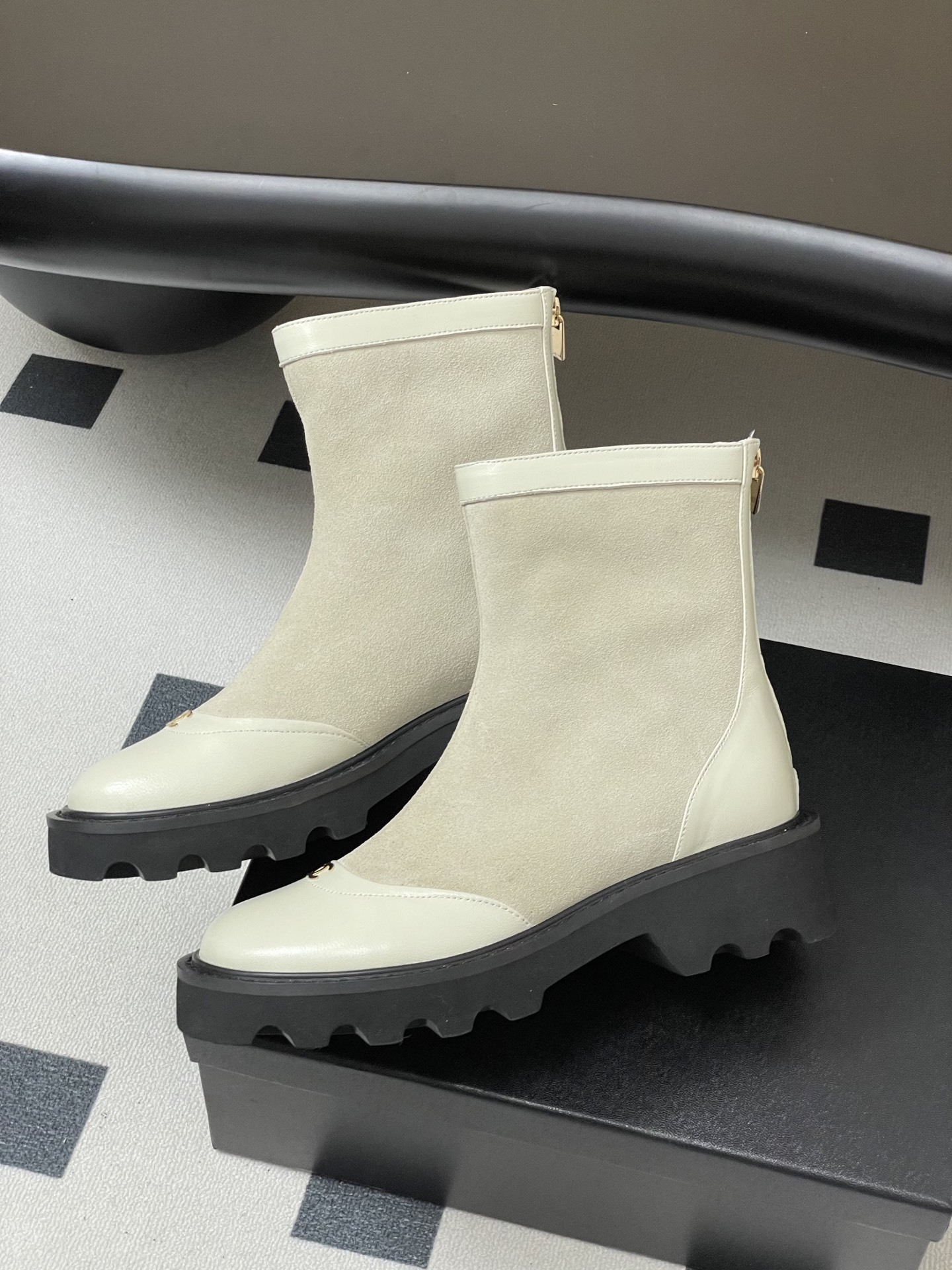Pair of luxury off-white suede and leather ankle boots with black chunky lug soles and gold-tone logo detail on the toe cap. - Hình 4