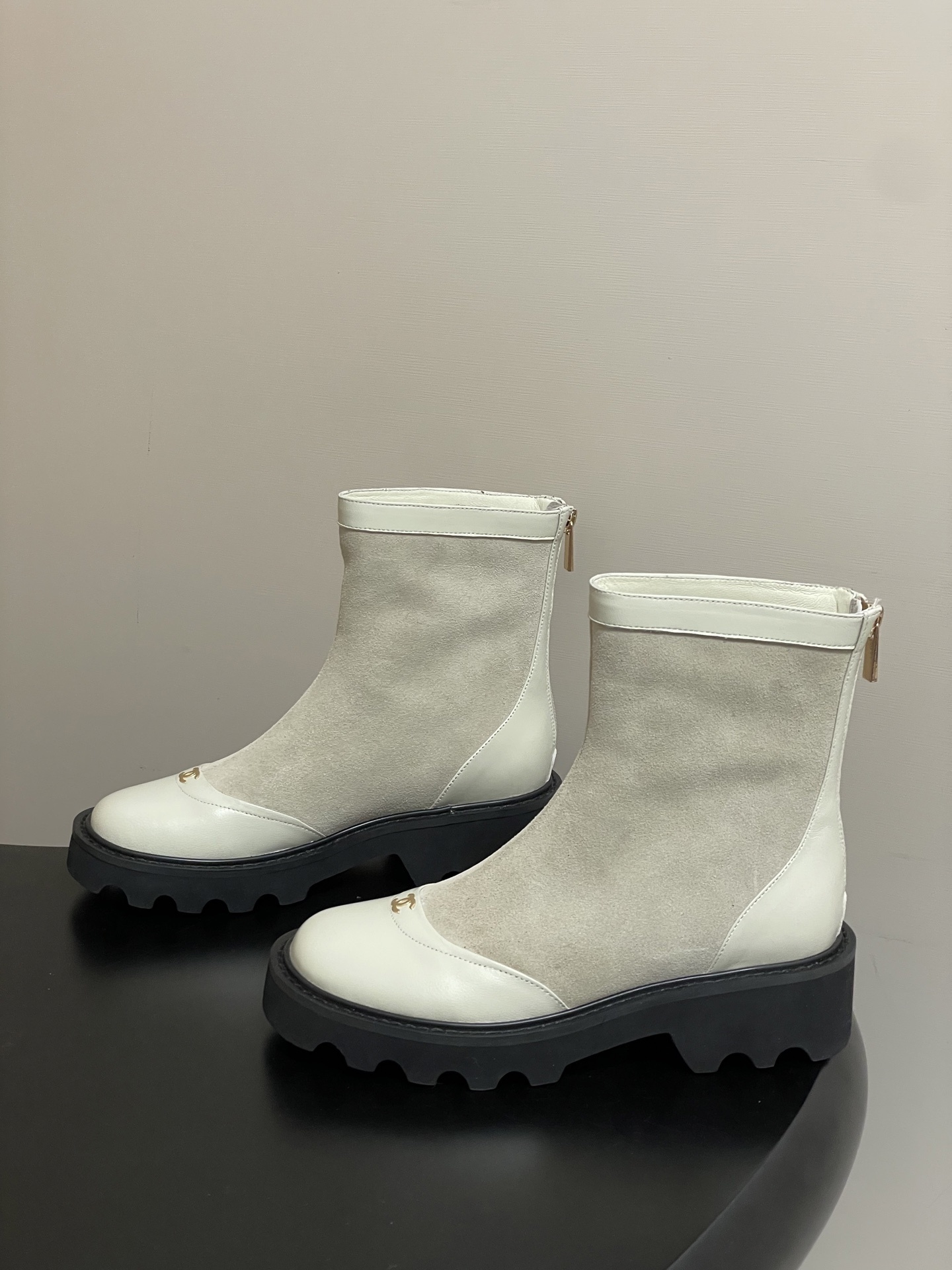 Pair of luxury off-white suede and leather ankle boots with black chunky lug soles and gold-tone logo detail on the toe cap. - Hình 3