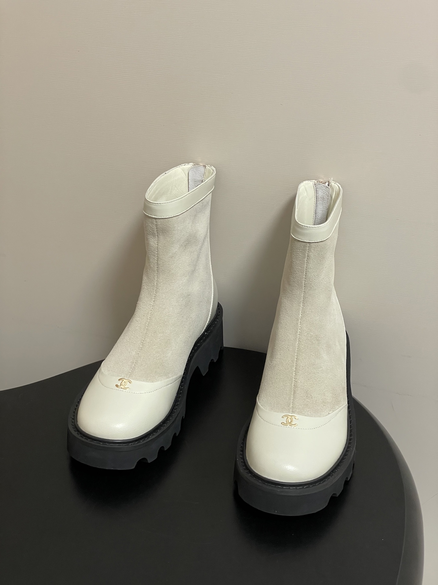 Pair of luxury off-white suede and leather ankle boots with black chunky lug soles and gold-tone logo detail on the toe cap. - Hình 2