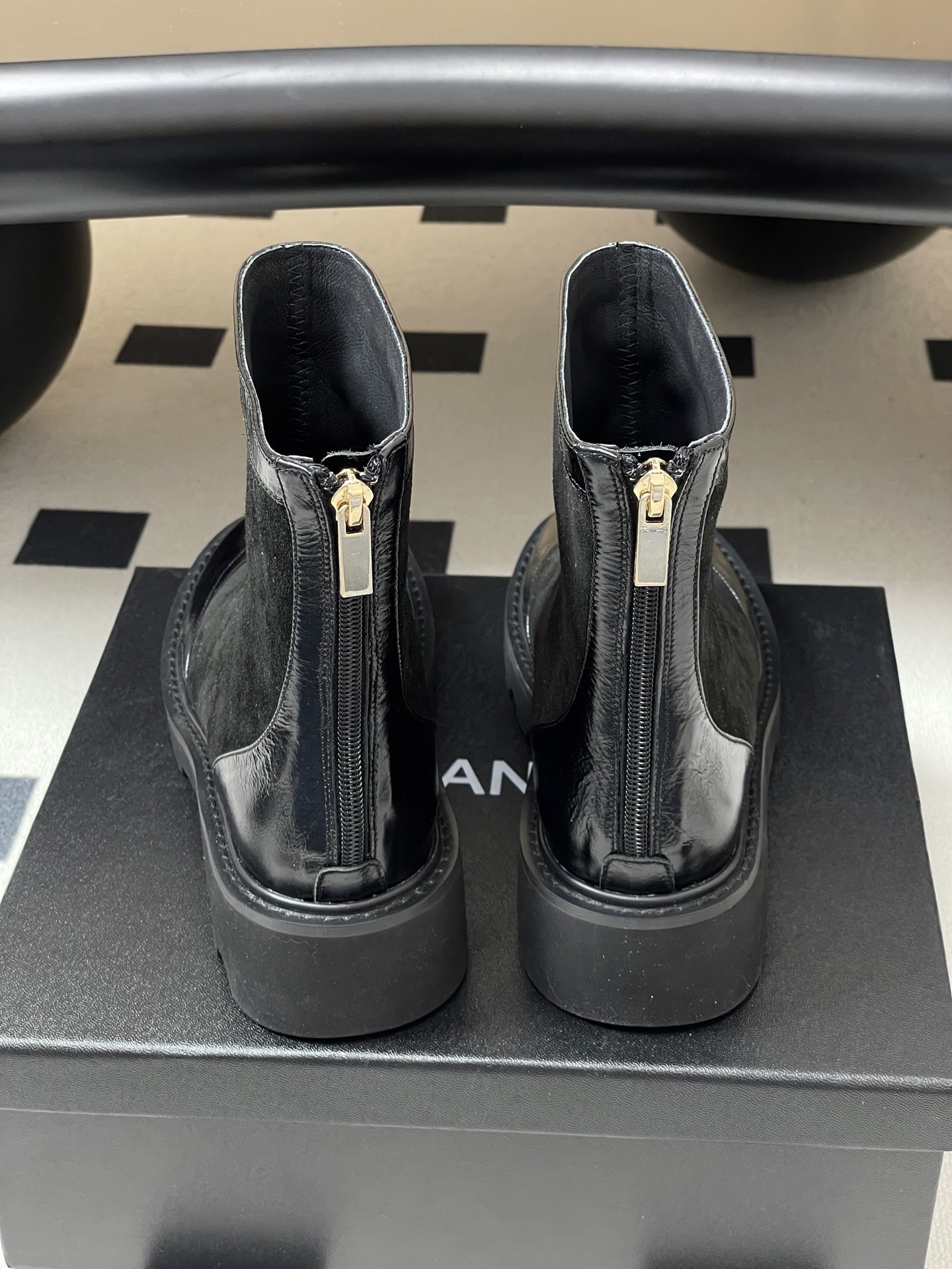 A pair of Chanel black suede ankle boots with patent leather toe caps, gold CC logos, and chunky lug soles. - Hình 9