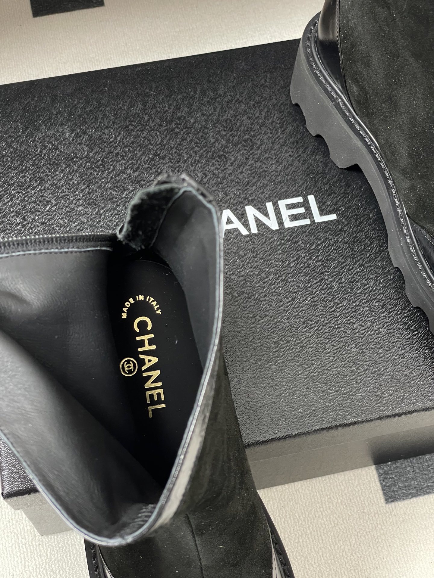 A pair of Chanel black suede ankle boots with patent leather toe caps, gold CC logos, and chunky lug soles. - Hình 6