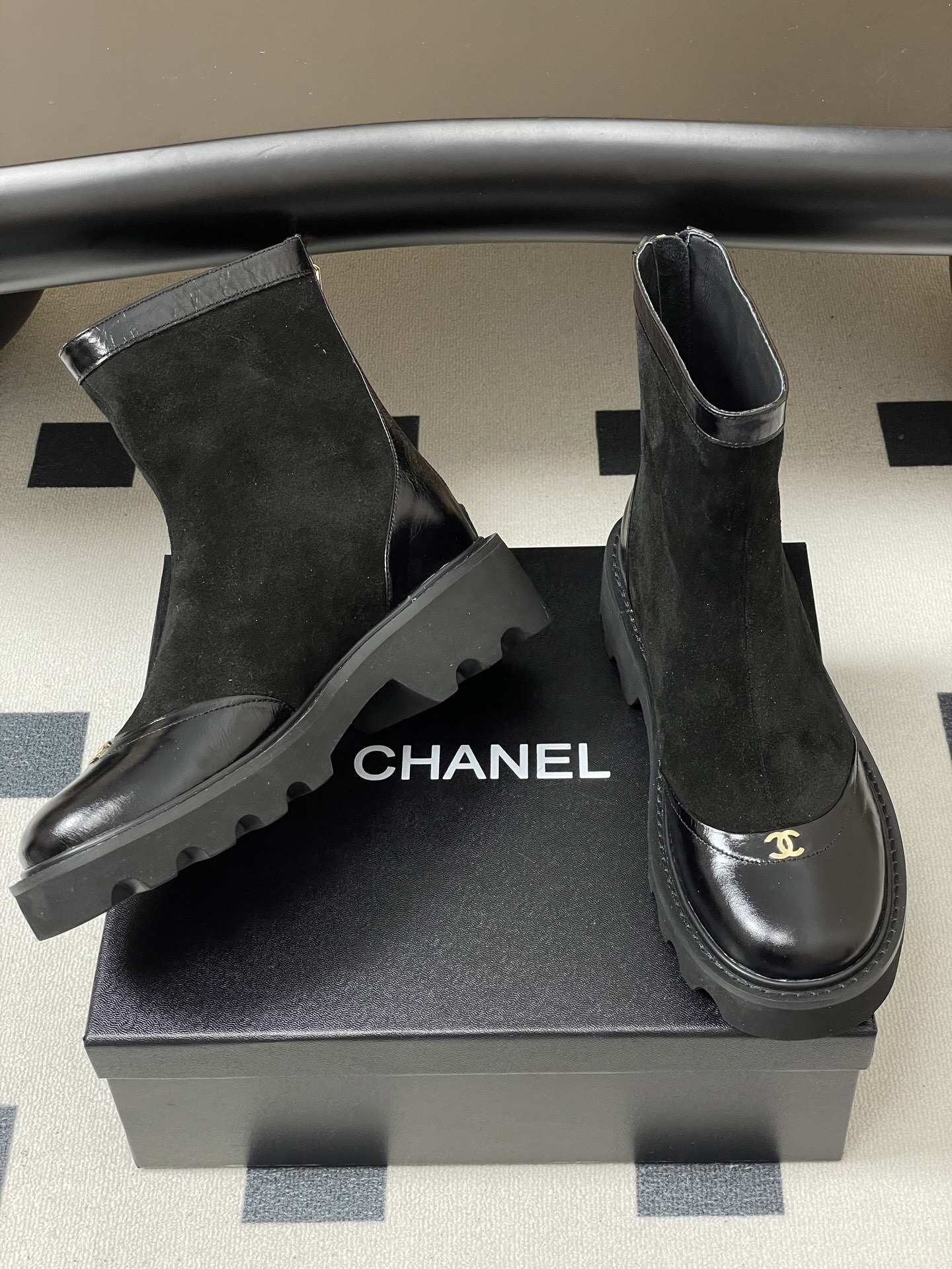 A pair of Chanel black suede ankle boots with patent leather toe caps, gold CC logos, and chunky lug soles. - Hình 5