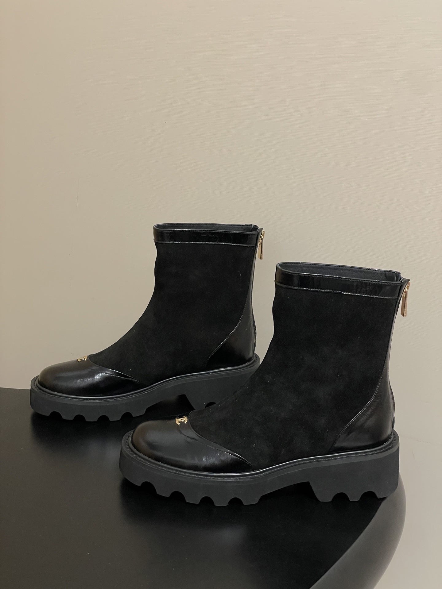 A pair of Chanel black suede ankle boots with patent leather toe caps, gold CC logos, and chunky lug soles. - Hình 3