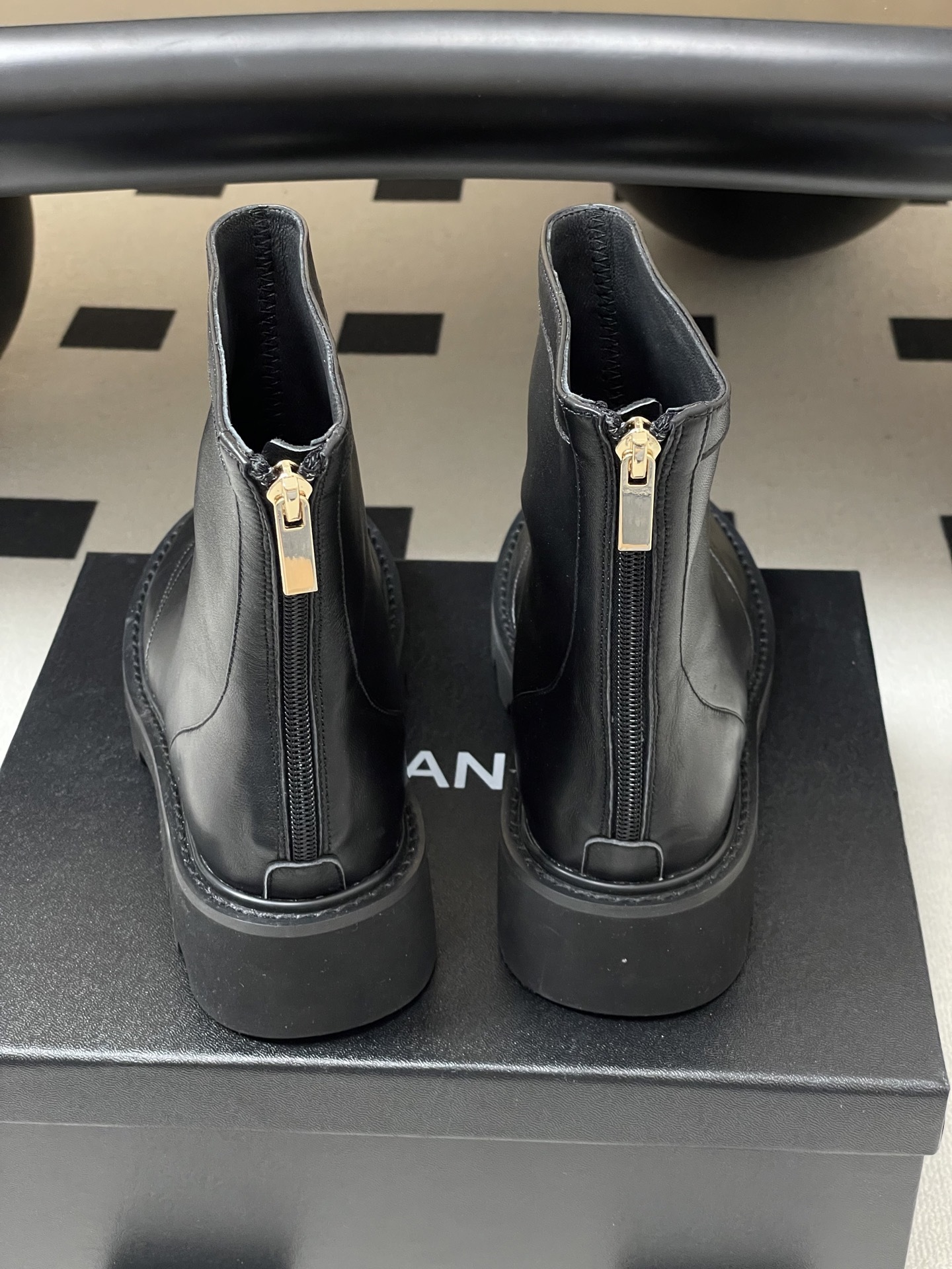 Pair of black leather ankle boots with chunky lug soles and gold interlocking logo on the toe - Hình 9