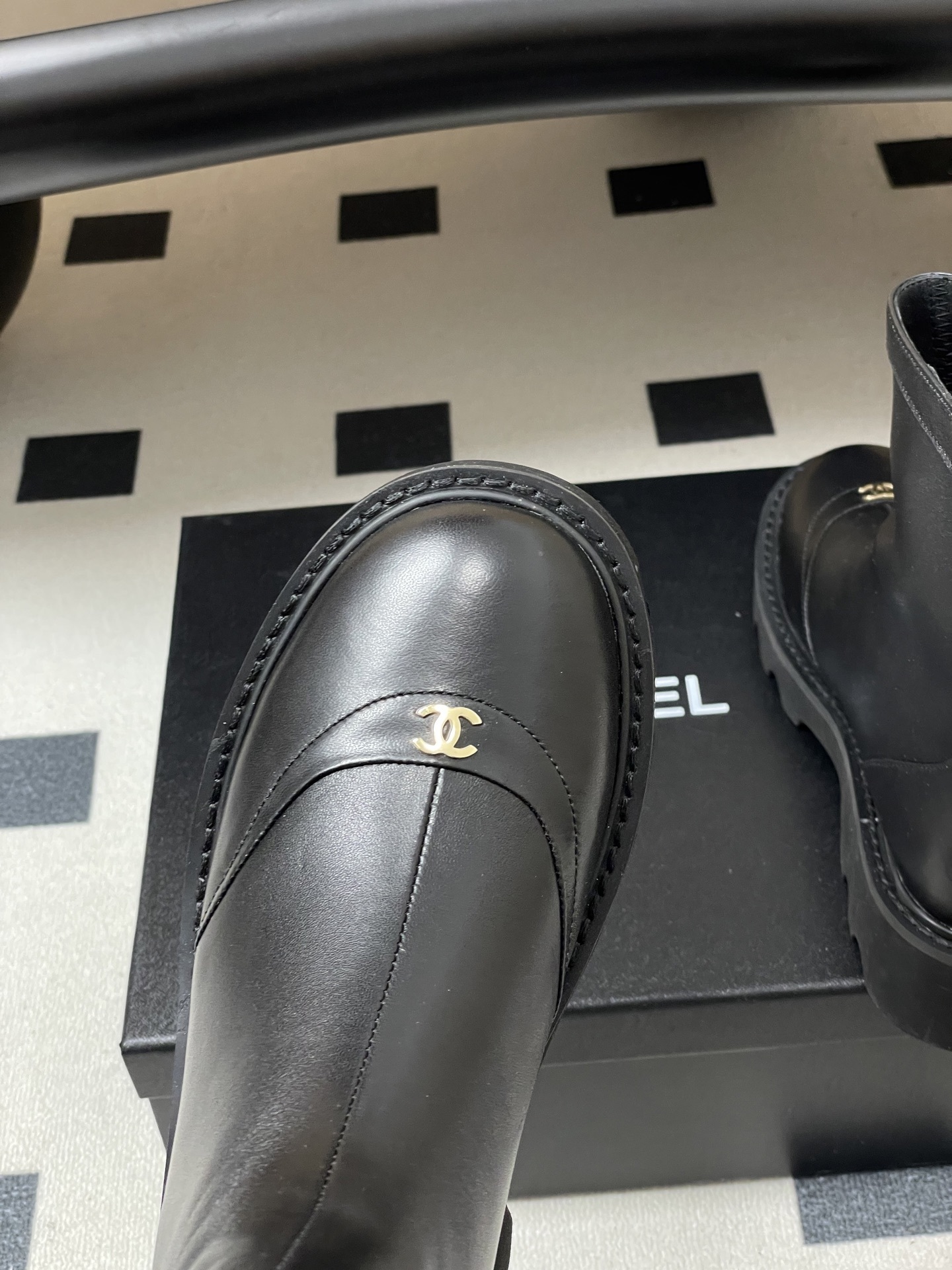 Pair of black leather ankle boots with chunky lug soles and gold interlocking logo on the toe - Hình 7