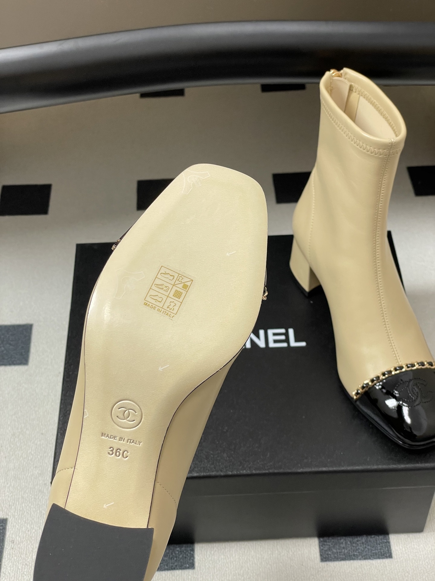Pair of elegant beige leather ankle boots with black patent cap toes and gold chain detailing - Hình 8