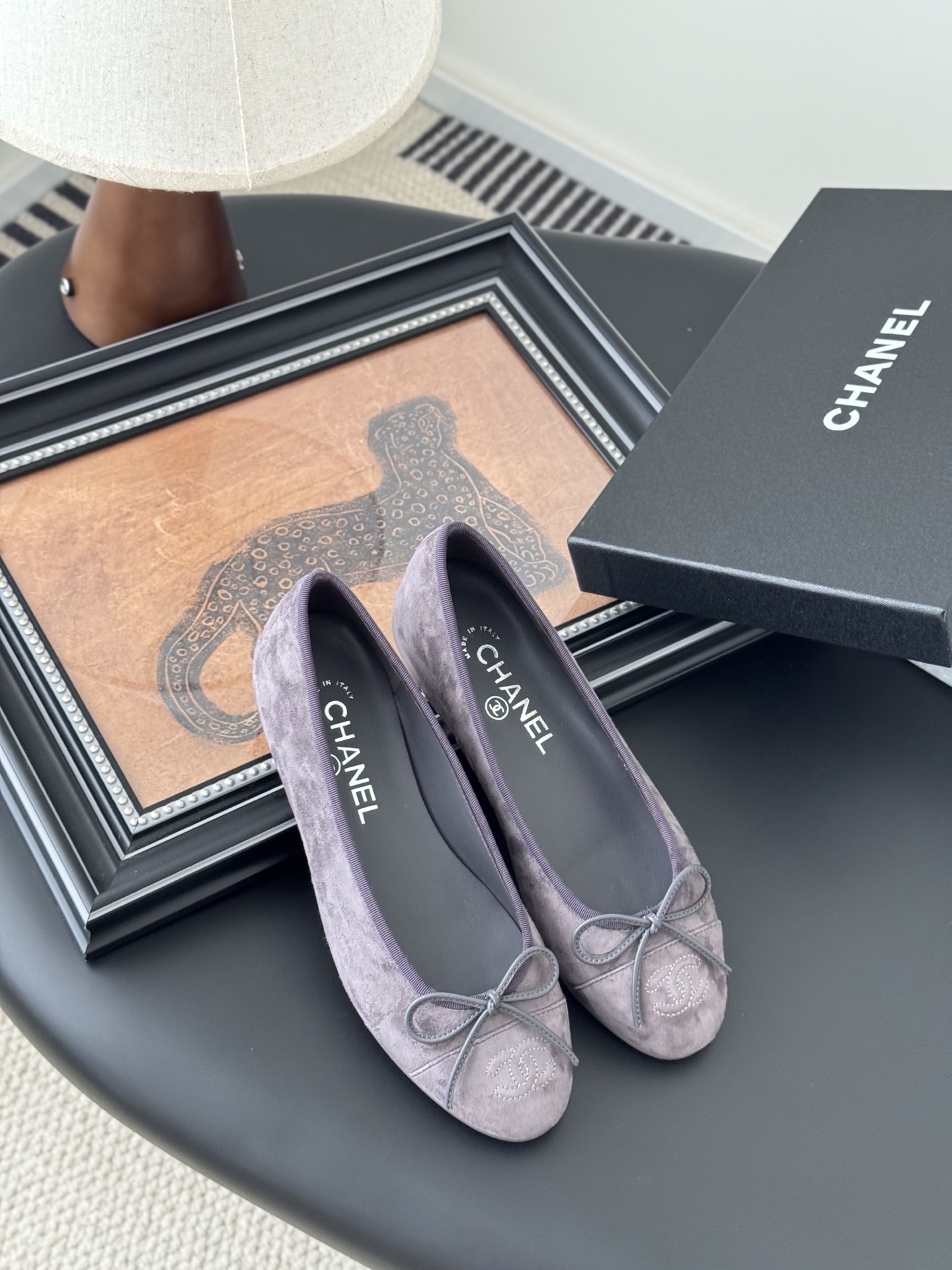 A pair of mauve suede Chanel ballerina flats featuring a bow and CC logo, displayed with a Chanel box. - Hình 7
