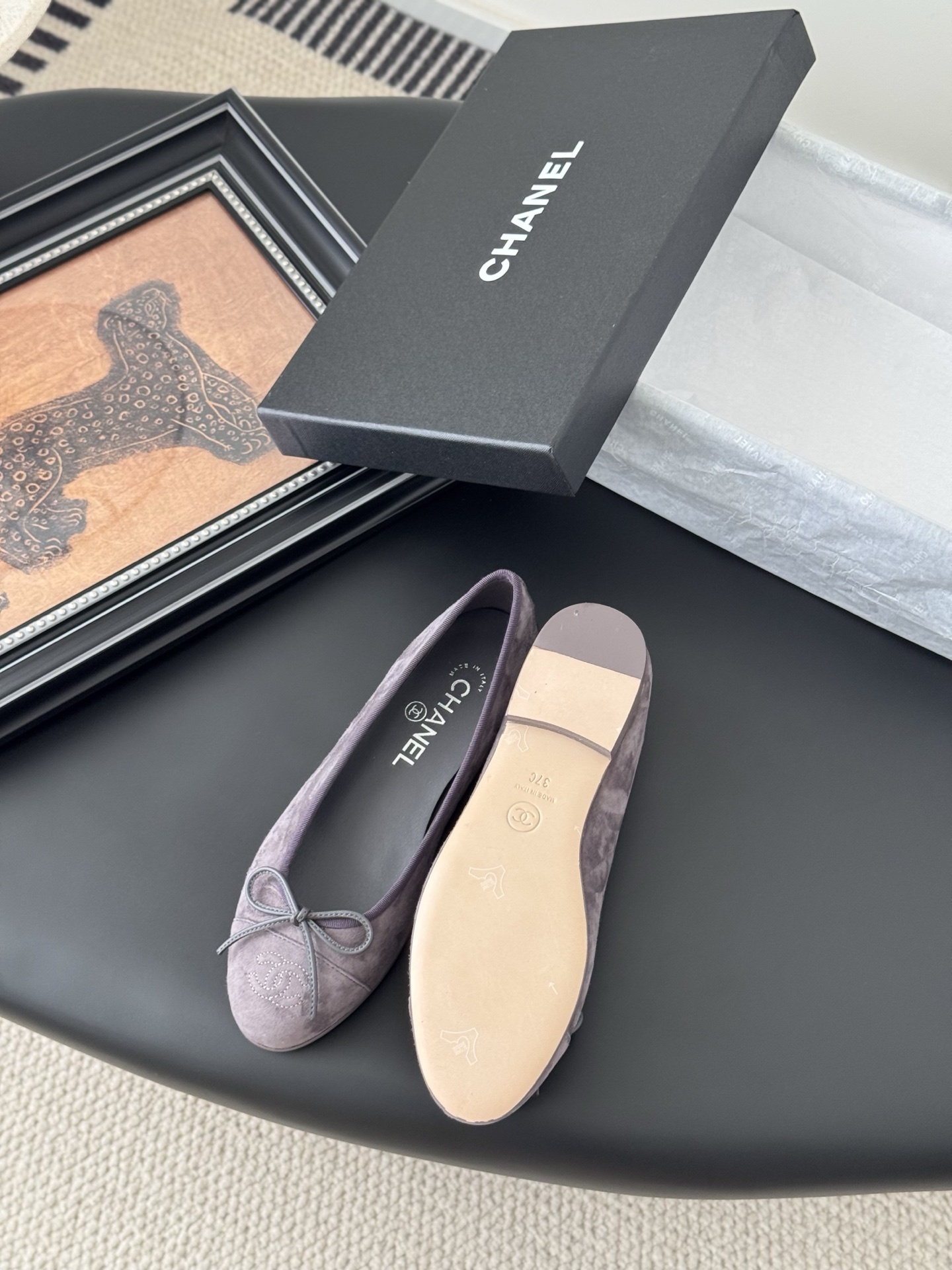 A pair of mauve suede Chanel ballerina flats featuring a bow and CC logo, displayed with a Chanel box. - Hình 4