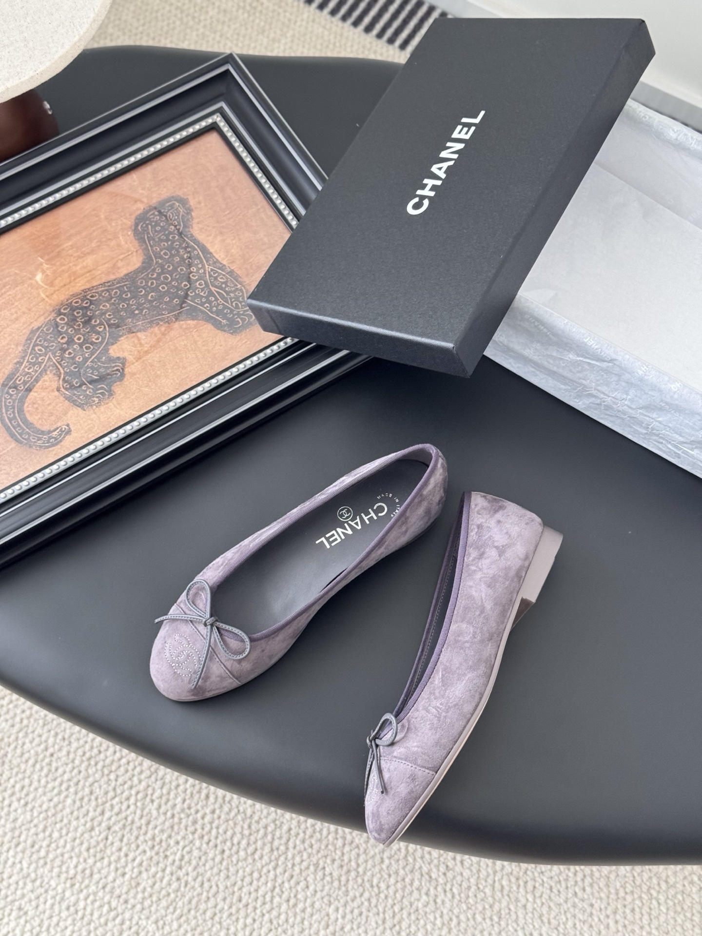 A pair of mauve suede Chanel ballerina flats featuring a bow and CC logo, displayed with a Chanel box. - Hình 3