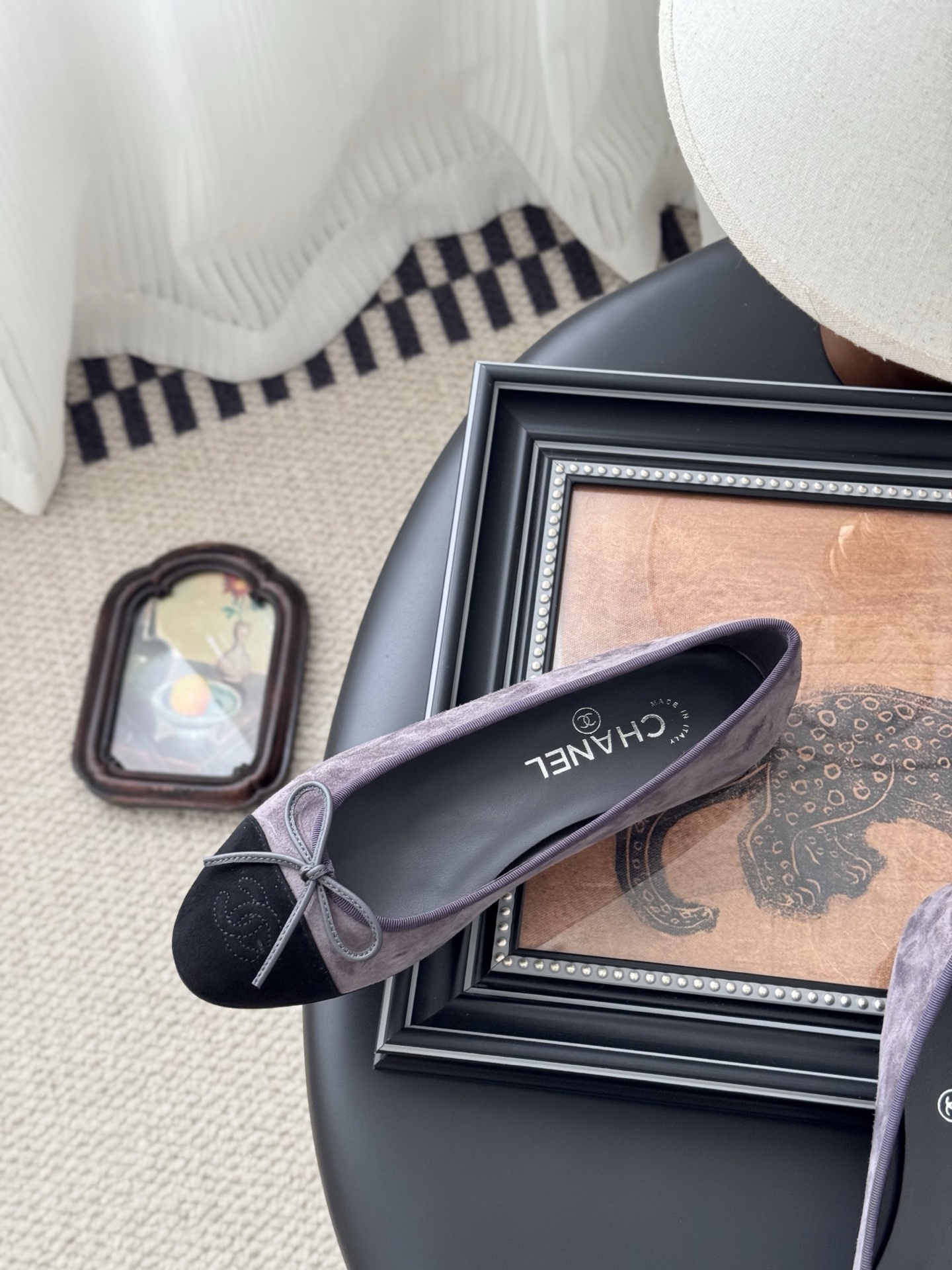 A pair of Chanel mauve suede ballet flats with black toe caps and bow detail next to an original Chanel box. - Hình 8