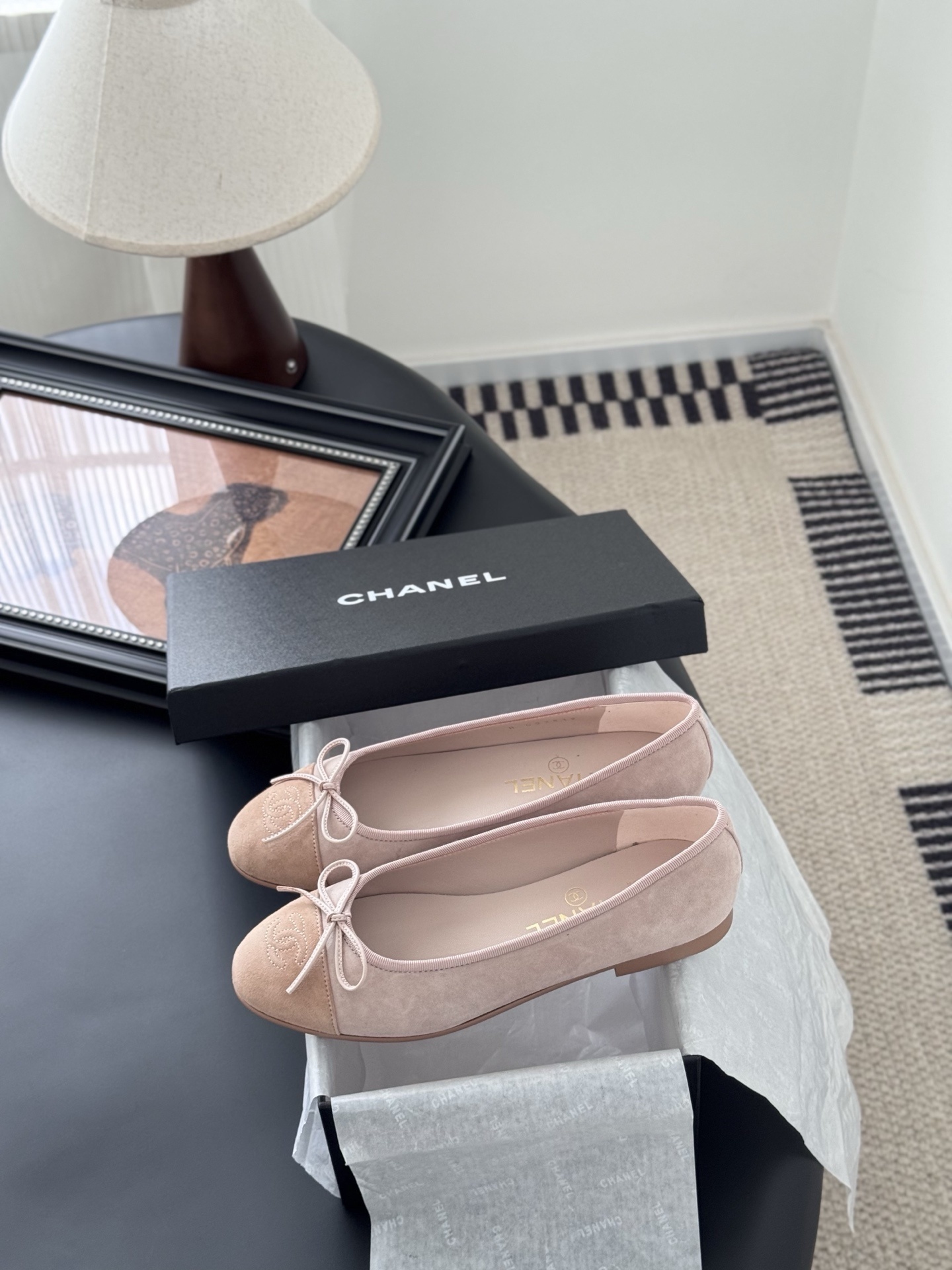 Pair of Chanel pink suede ballet flats with CC logo and bow detail next to a black shoe box - Hình 9