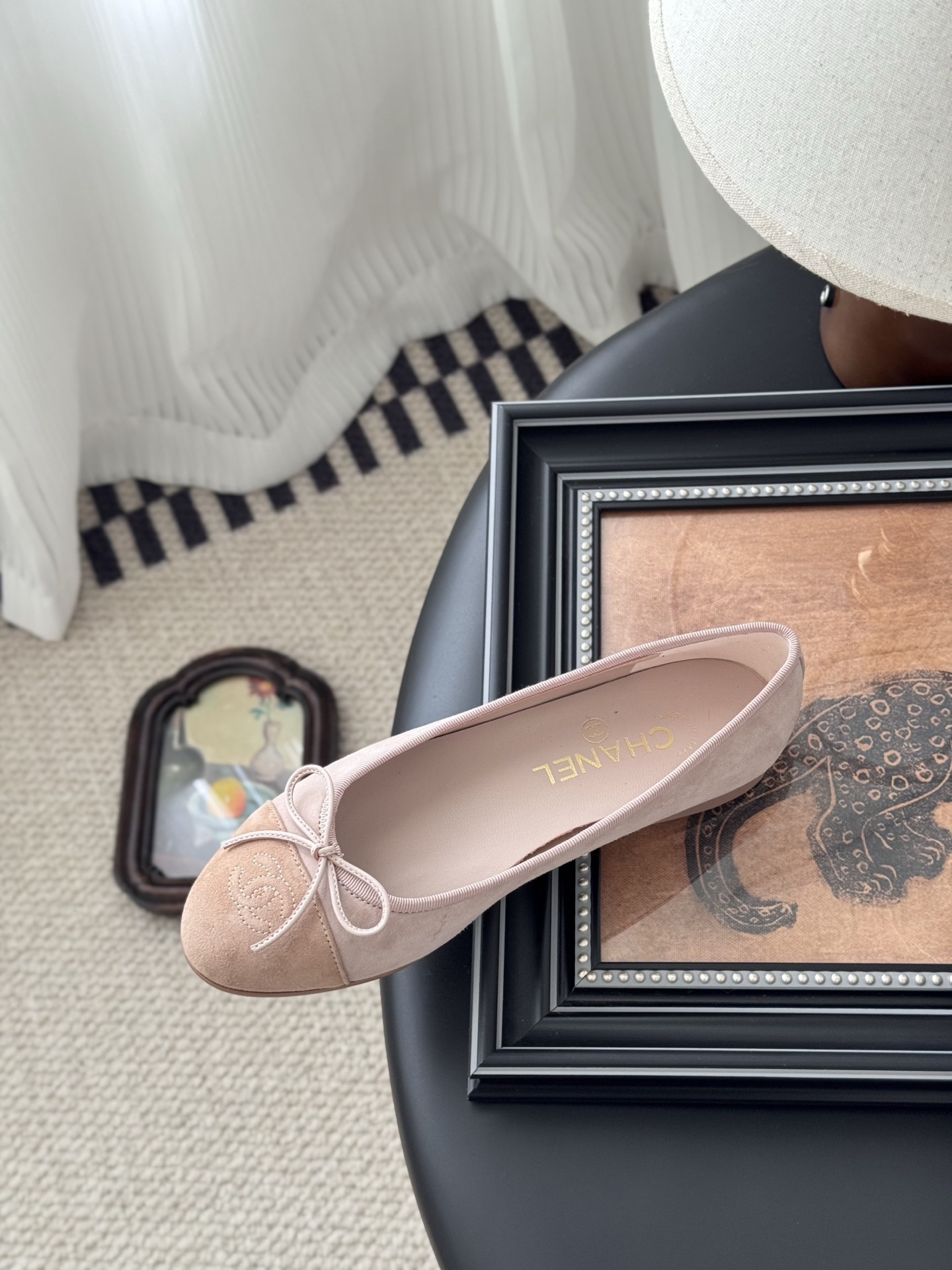 Pair of Chanel pink suede ballet flats with CC logo and bow detail next to a black shoe box - Hình 8