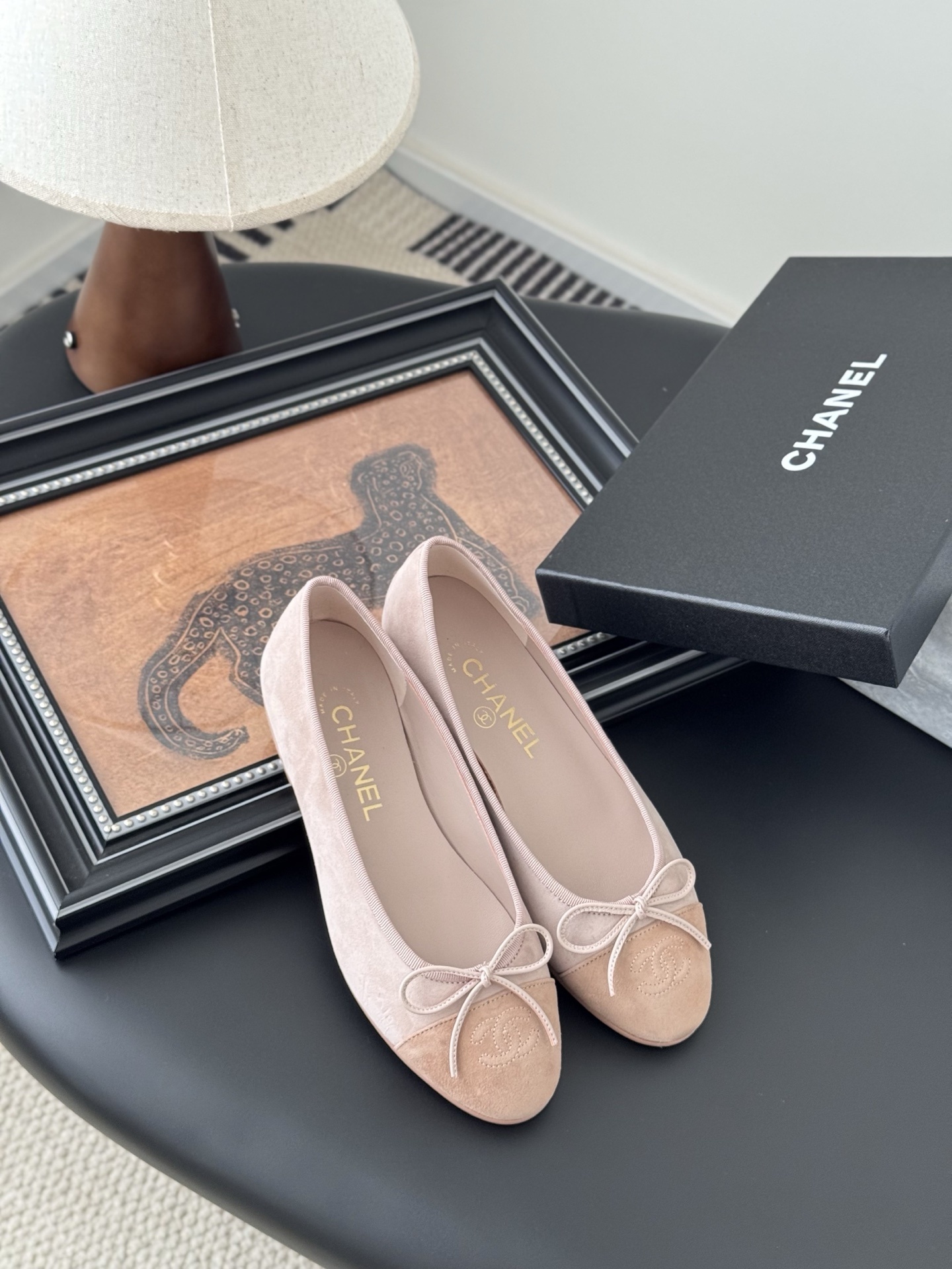 Pair of Chanel pink suede ballet flats with CC logo and bow detail next to a black shoe box - Hình 7