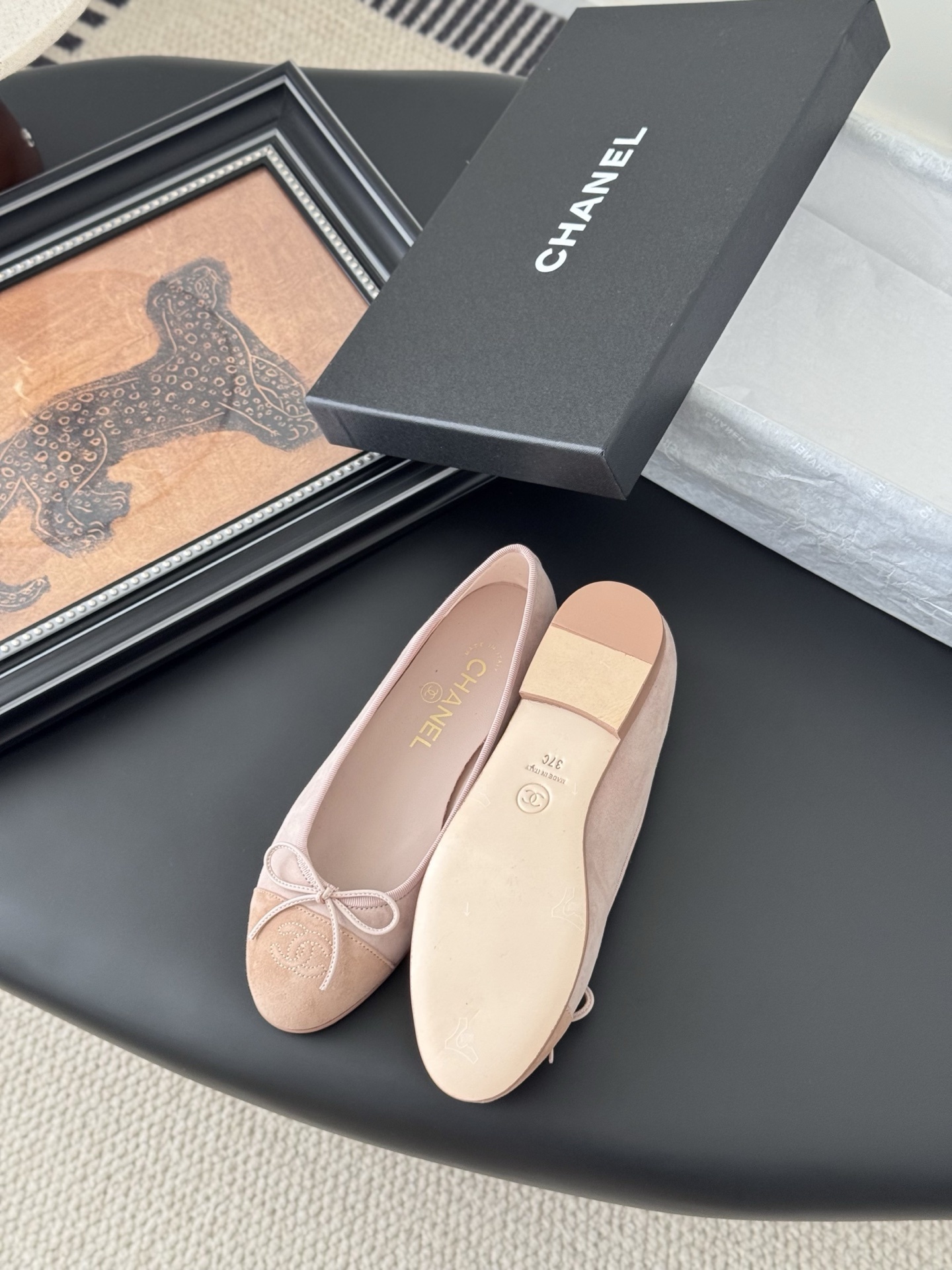 Pair of Chanel pink suede ballet flats with CC logo and bow detail next to a black shoe box - Hình 4