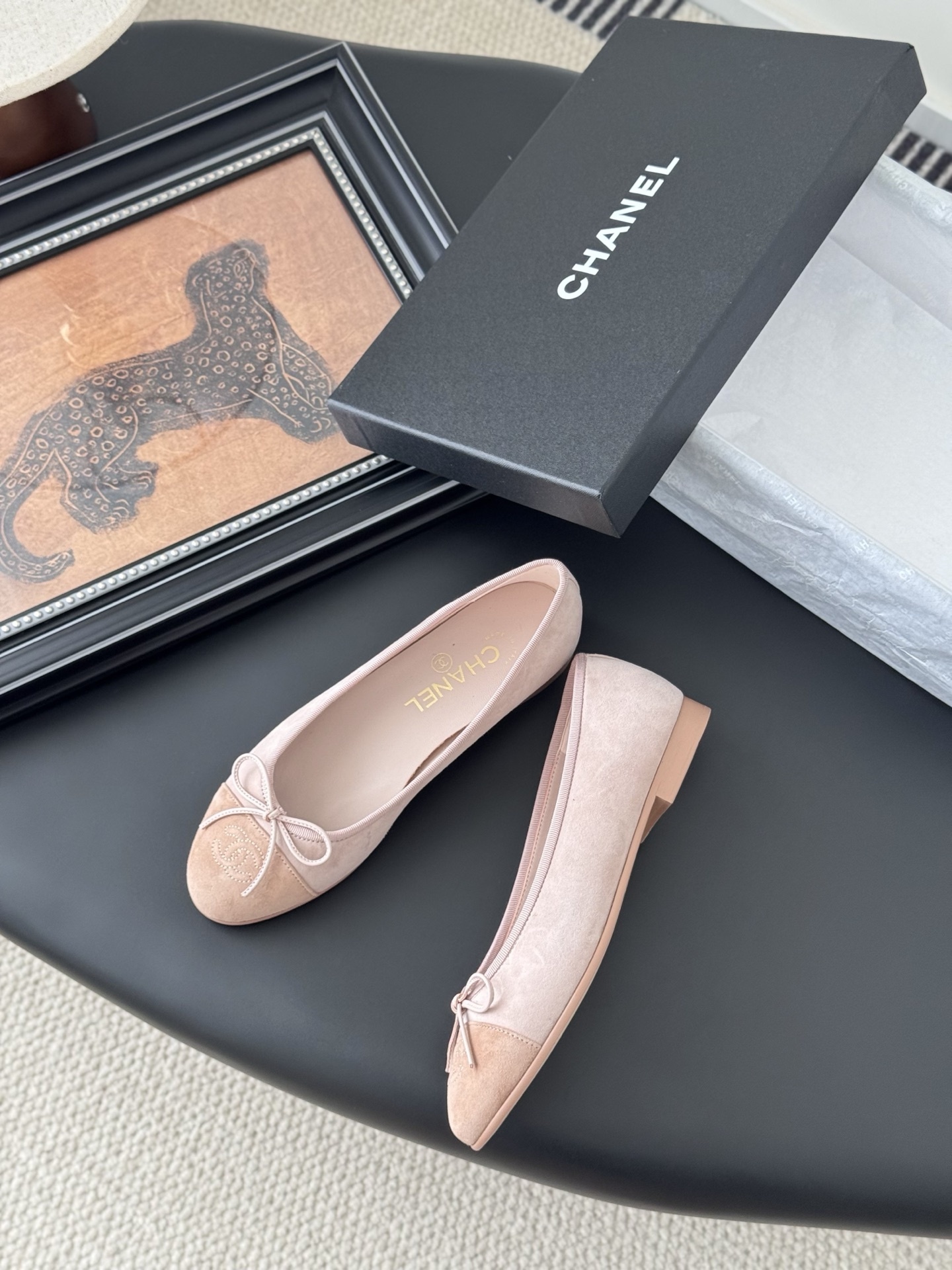 Pair of Chanel pink suede ballet flats with CC logo and bow detail next to a black shoe box - Hình 3