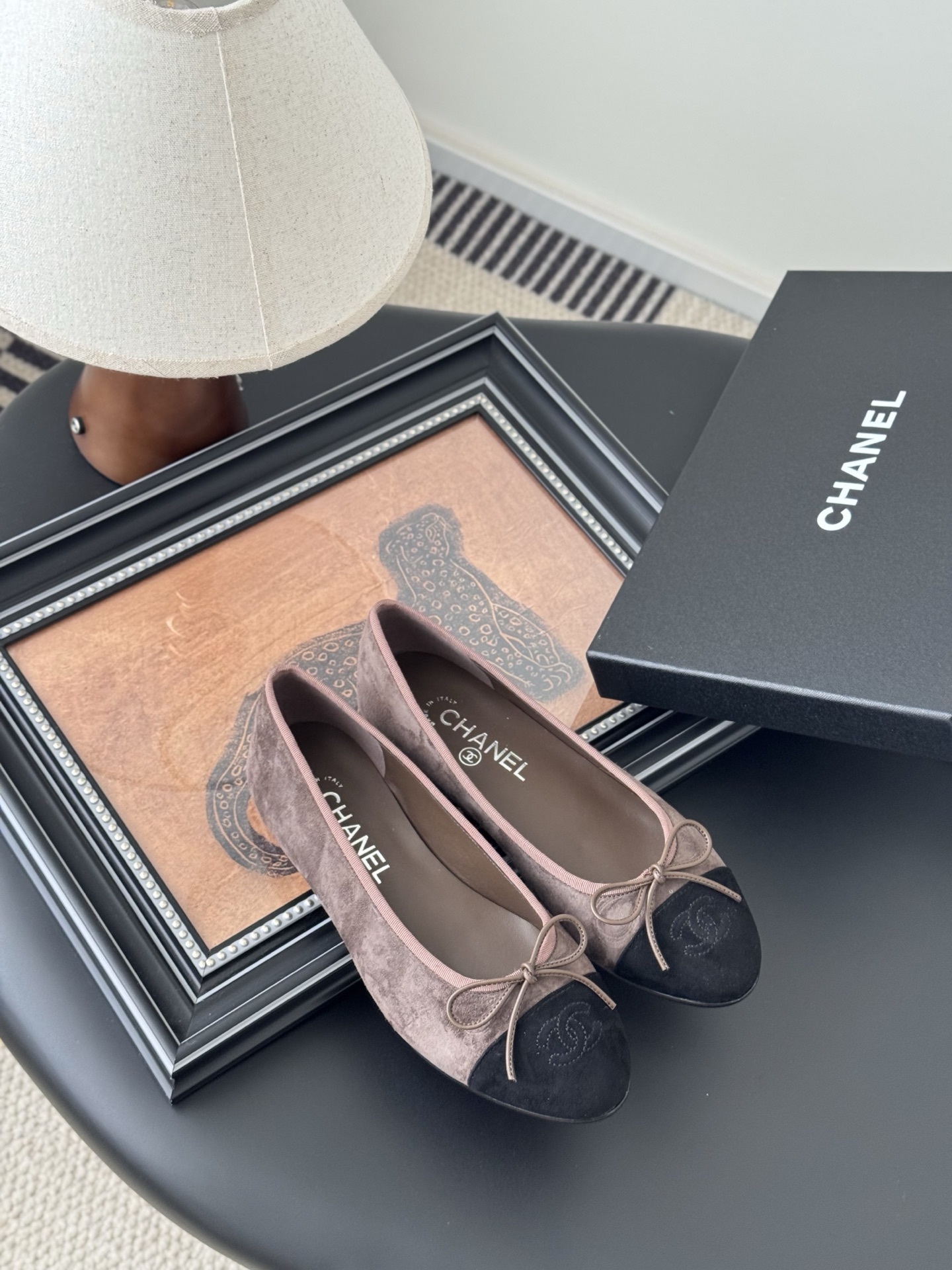 Luxury Chanel brown suede ballerina flats with black cap toe and bow detail placed next to a Chanel shoe box. - Hình 7
