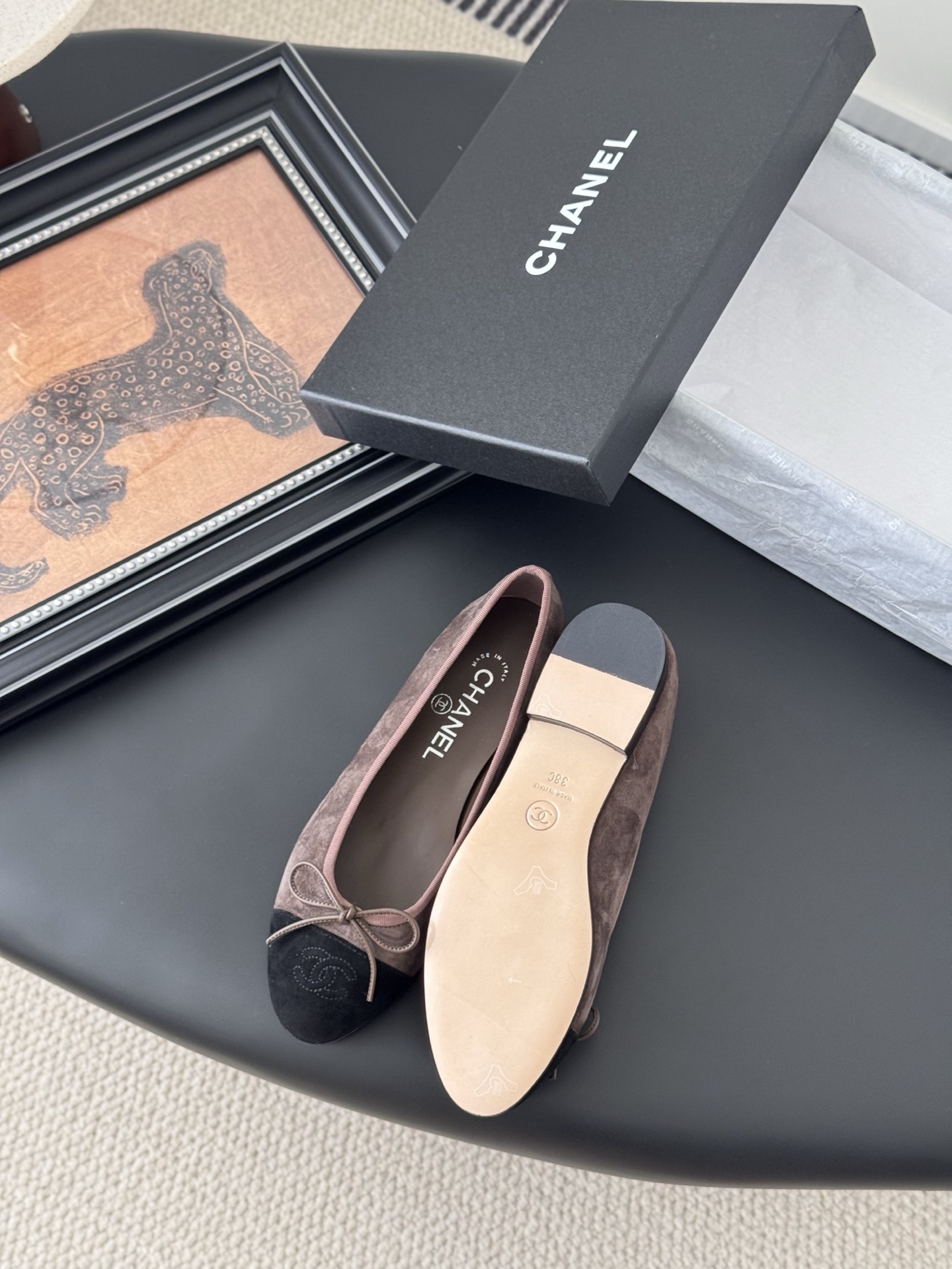 Luxury Chanel brown suede ballerina flats with black cap toe and bow detail placed next to a Chanel shoe box. - Hình 4