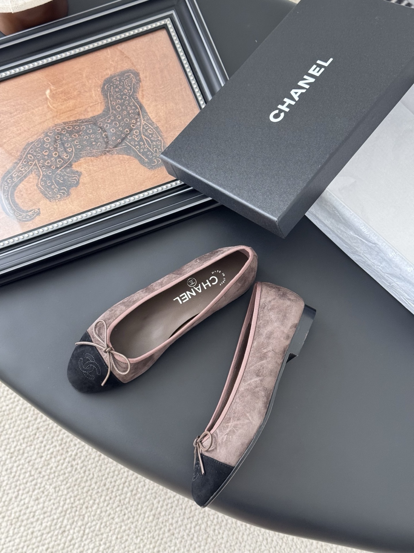 Luxury Chanel brown suede ballerina flats with black cap toe and bow detail placed next to a Chanel shoe box. - Hình 3