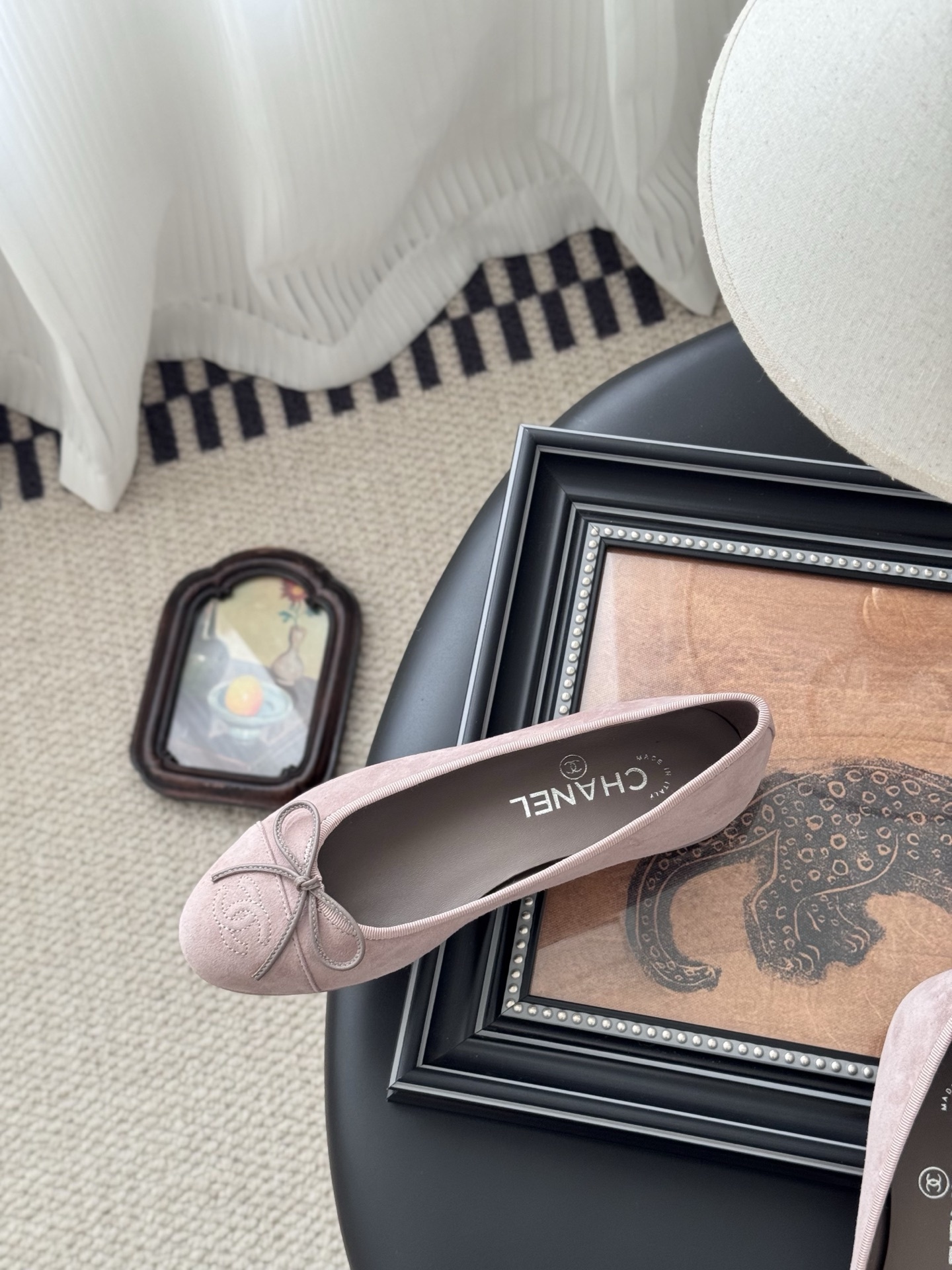 A pair of elegant pink Chanel suede ballet flats with a bow and CC logo on the toe, shown with the original black Chanel box. - Hình 8