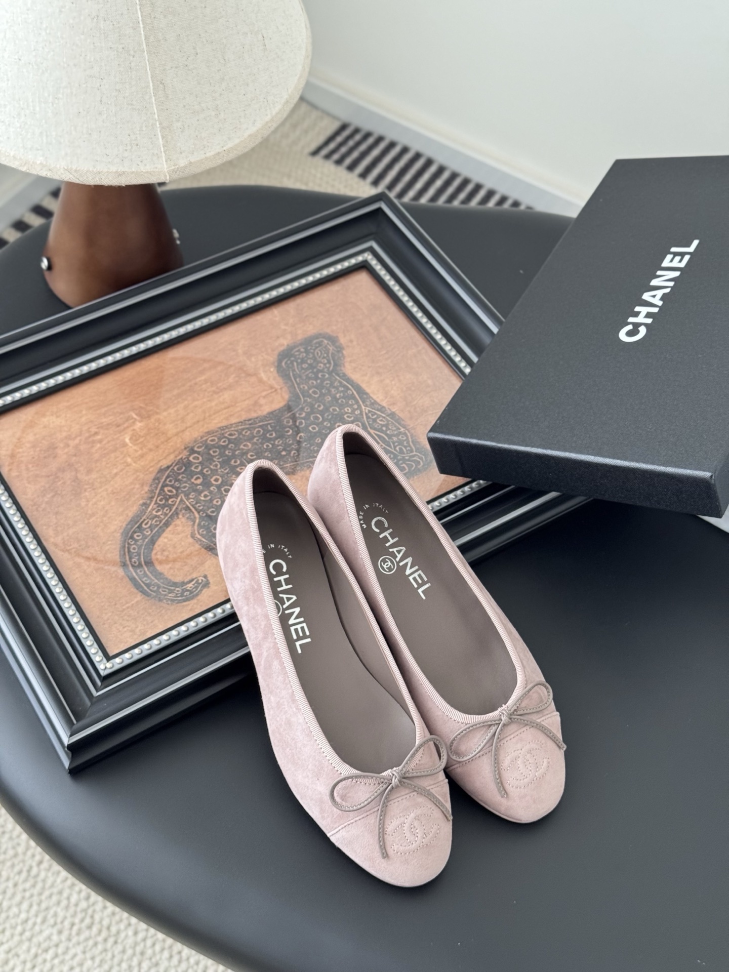 A pair of elegant pink Chanel suede ballet flats with a bow and CC logo on the toe, shown with the original black Chanel box. - Hình 7