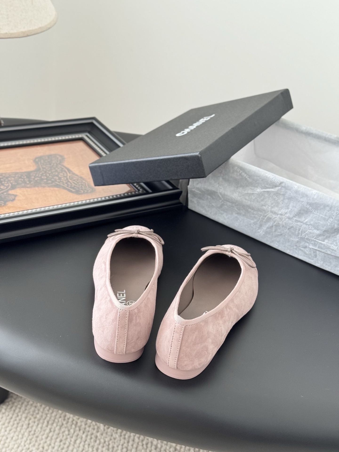 A pair of elegant pink Chanel suede ballet flats with a bow and CC logo on the toe, shown with the original black Chanel box. - Hình 6