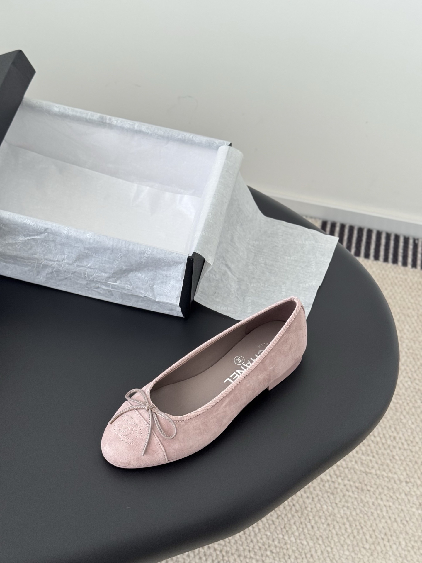 A pair of elegant pink Chanel suede ballet flats with a bow and CC logo on the toe, shown with the original black Chanel box. - Hình 5