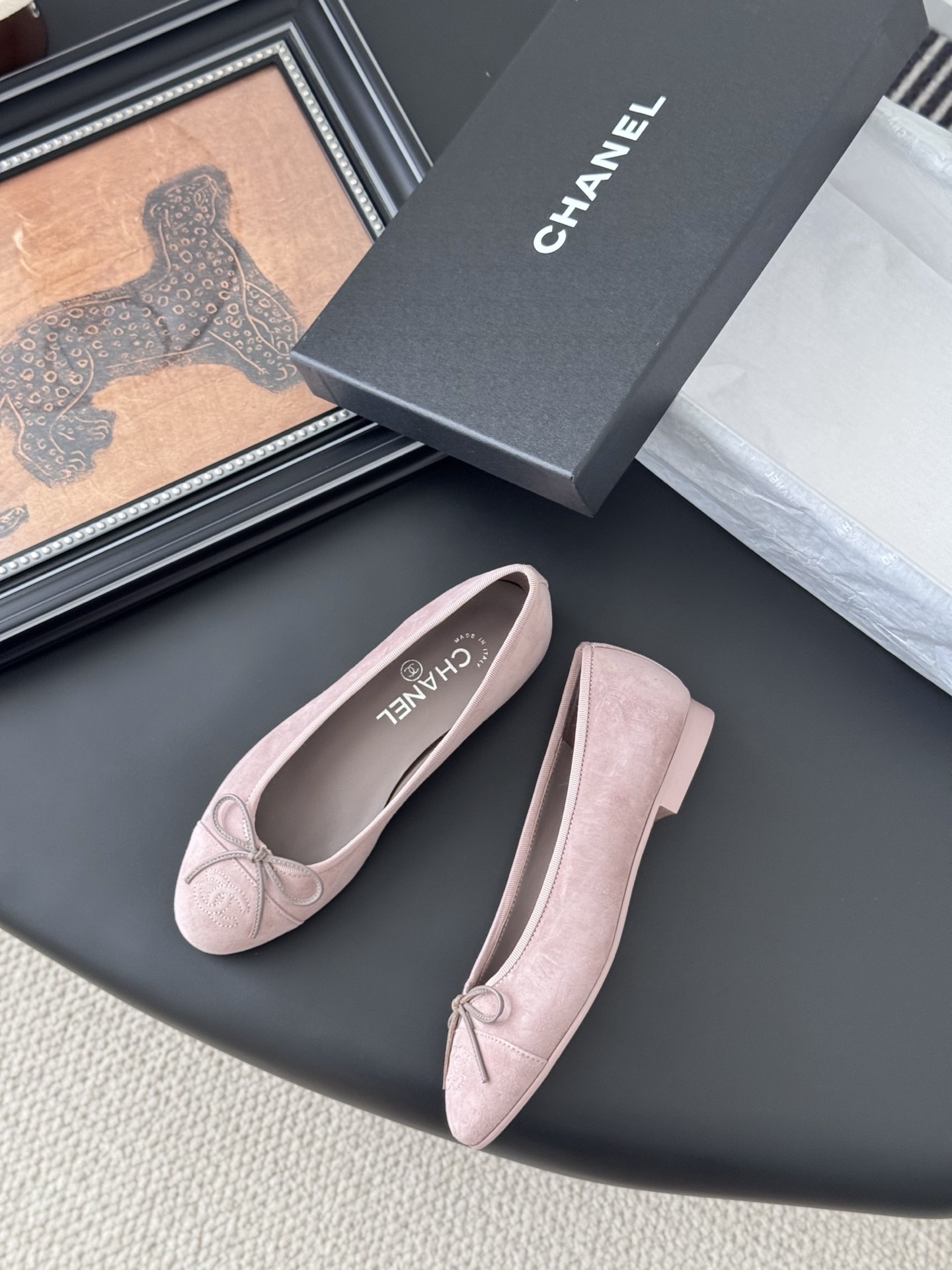 A pair of elegant pink Chanel suede ballet flats with a bow and CC logo on the toe, shown with the original black Chanel box. - Hình 3