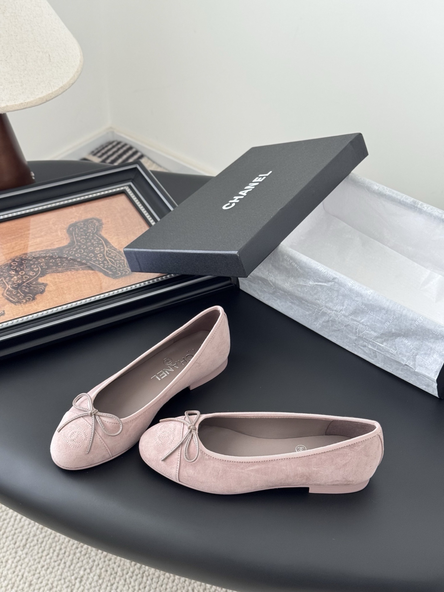 A pair of elegant pink Chanel suede ballet flats with a bow and CC logo on the toe, shown with the original black Chanel box. - Hình 2