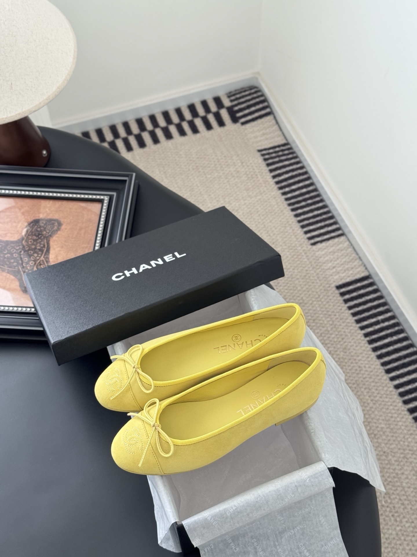 A pair of yellow Chanel suede ballerina flats with a bow and embroidered logo next to their original black box. - Hình 9