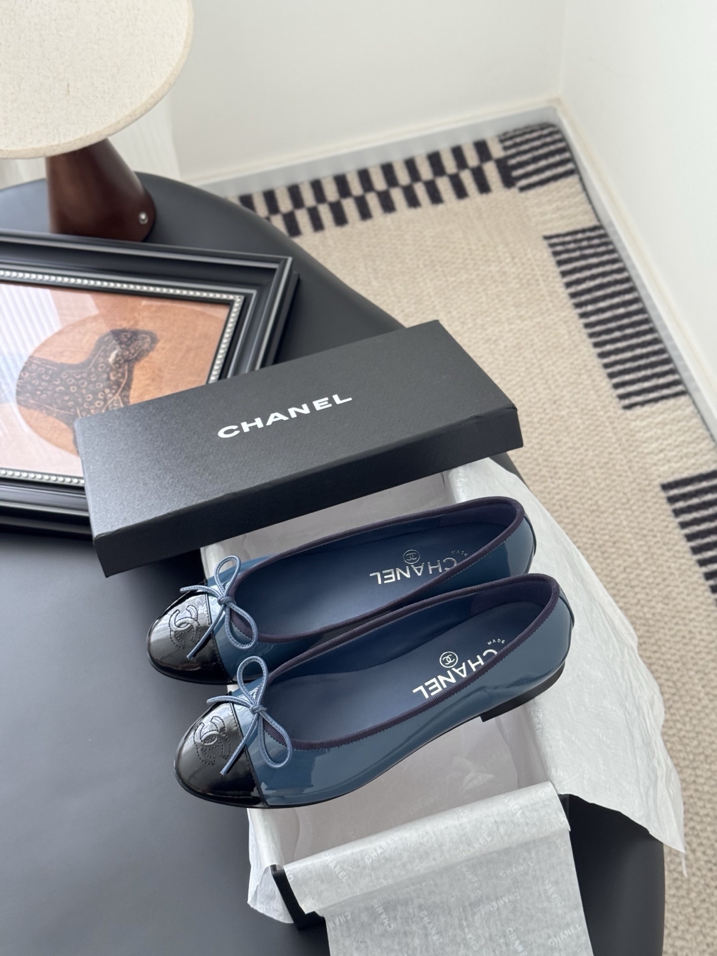 A pair of Chanel two-tone patent leather ballet flats in blue and black with a bow detail and CC logo, displayed with the original Chanel box. - Hình 9
