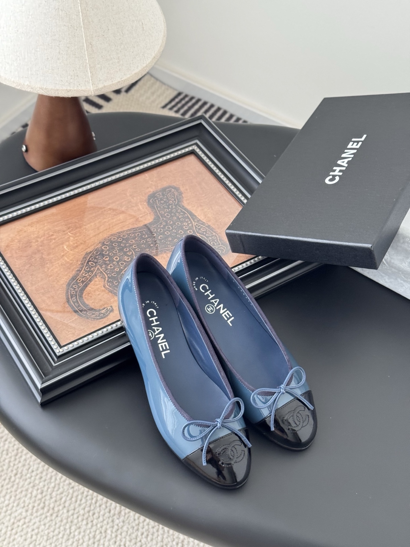 A pair of Chanel two-tone patent leather ballet flats in blue and black with a bow detail and CC logo, displayed with the original Chanel box. - Hình 7