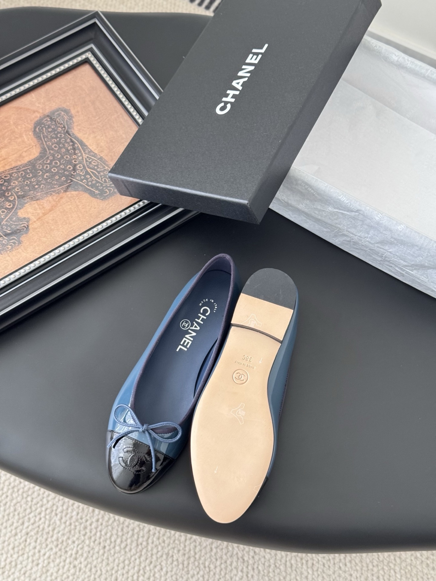 A pair of Chanel two-tone patent leather ballet flats in blue and black with a bow detail and CC logo, displayed with the original Chanel box. - Hình 4