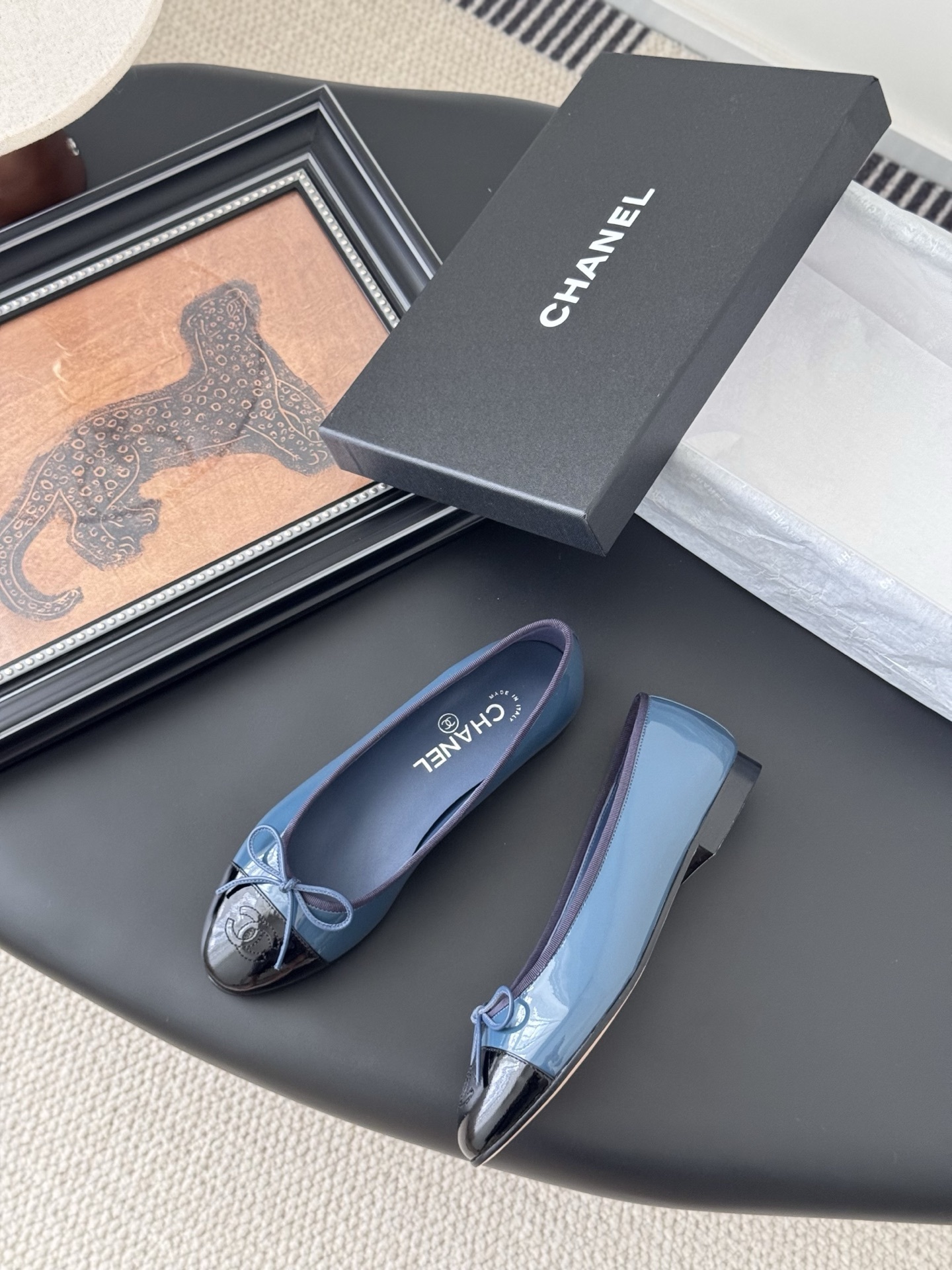 A pair of Chanel two-tone patent leather ballet flats in blue and black with a bow detail and CC logo, displayed with the original Chanel box. - Hình 3